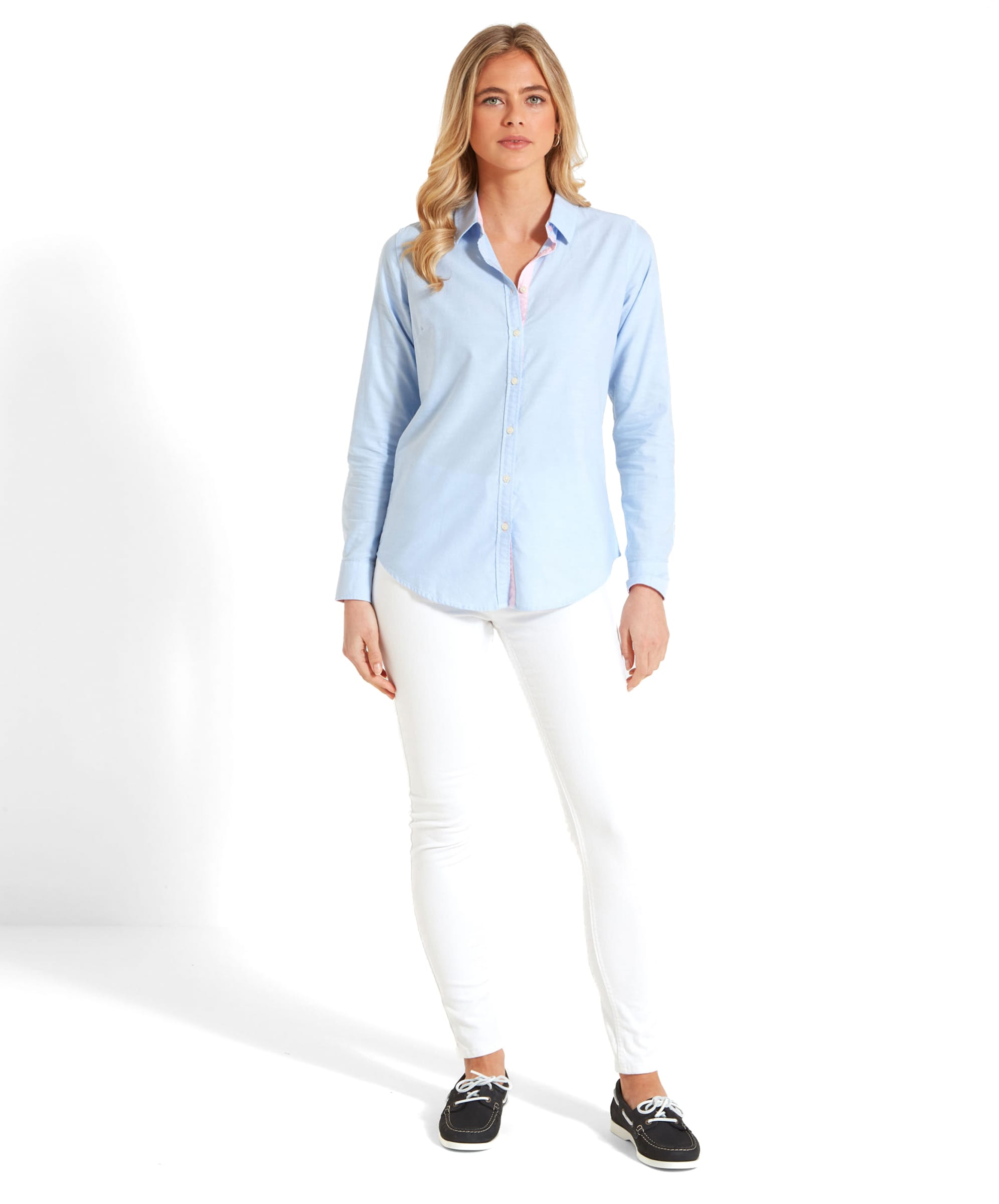 Full-body shot of the woman in a Schöffel Cley Women's Soft Oxford Shirt for Womens in Light Blue and white trousers, posing with both hands by her sides.