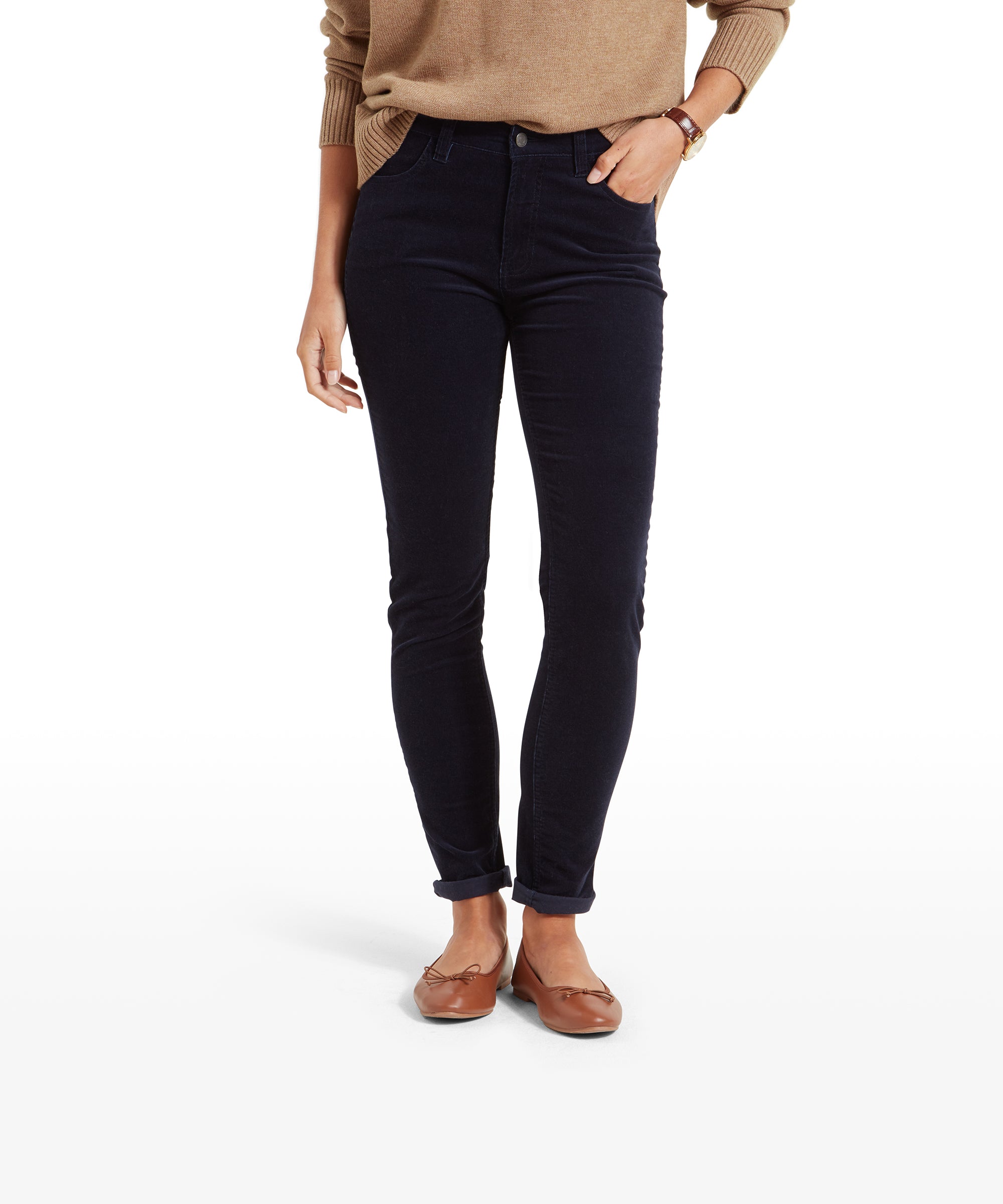 A woman wearing a beige sweater and Schöffel Clover Cord Jean for Womens in Navy. The jeans are slim fit and styled with the hems slightly rolled up. She is also wearing brown flat shoes.