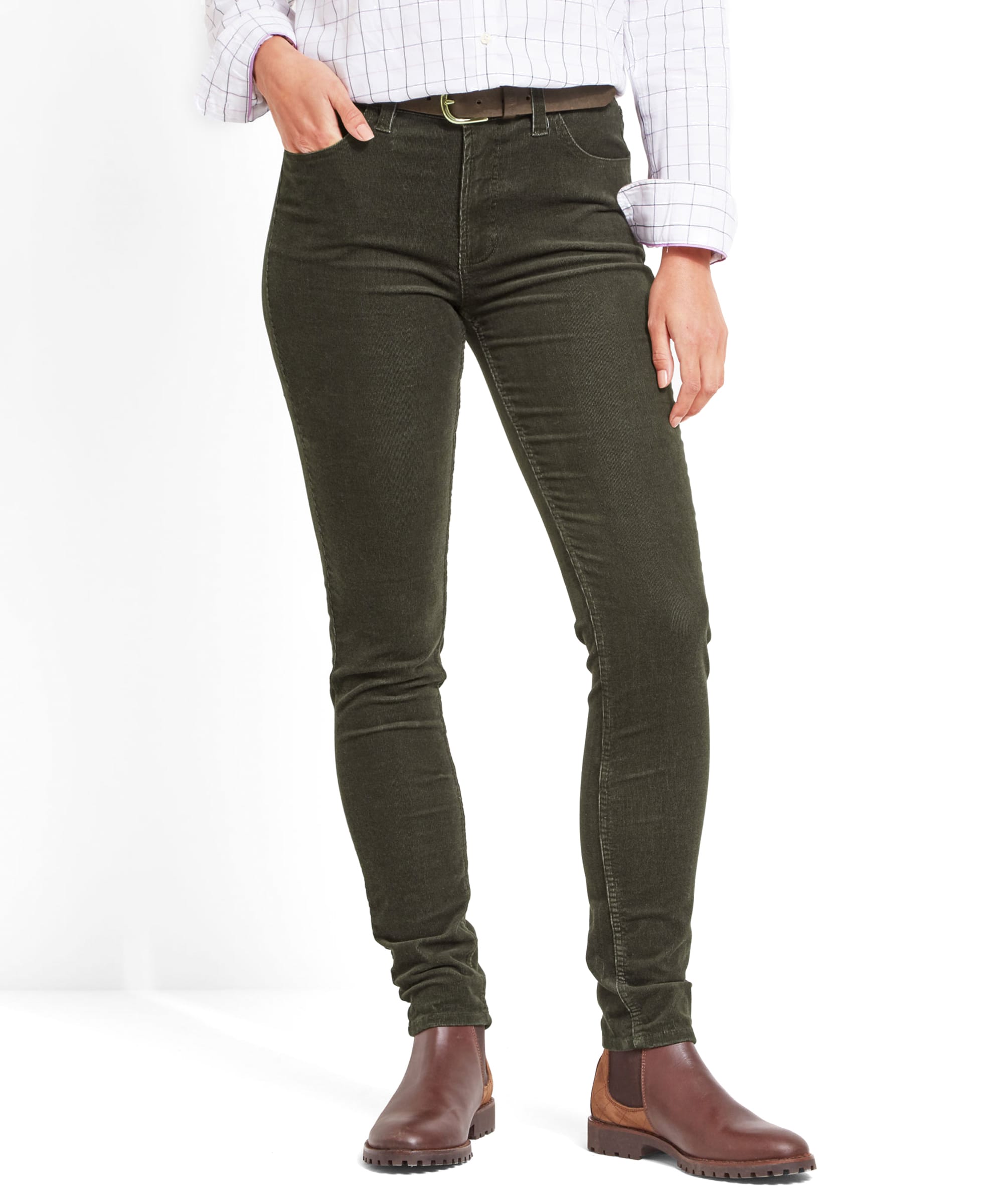 Close-up view of a model wearing Schöffel Clover Cord Jean for Womens in Green paired with a checked shirt. The jeans feature a slim fit design and the model is also wearing brown Chelsea boots.