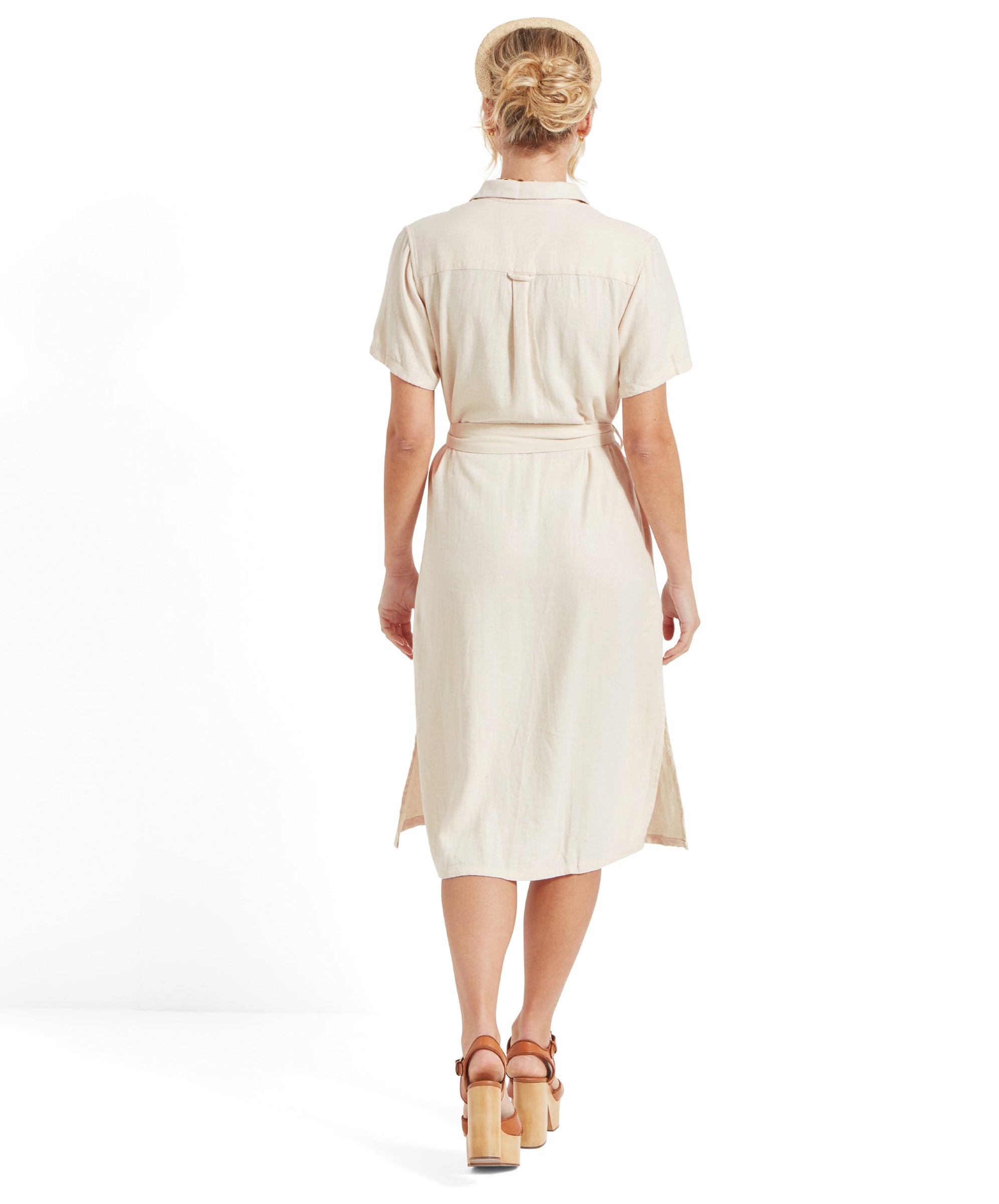 Rear view of the woman showcasing the back of Schöffel Daisy Linen Dress for Women in Light Brown, her hair tied up, and the hemline that reaches just below her knees.