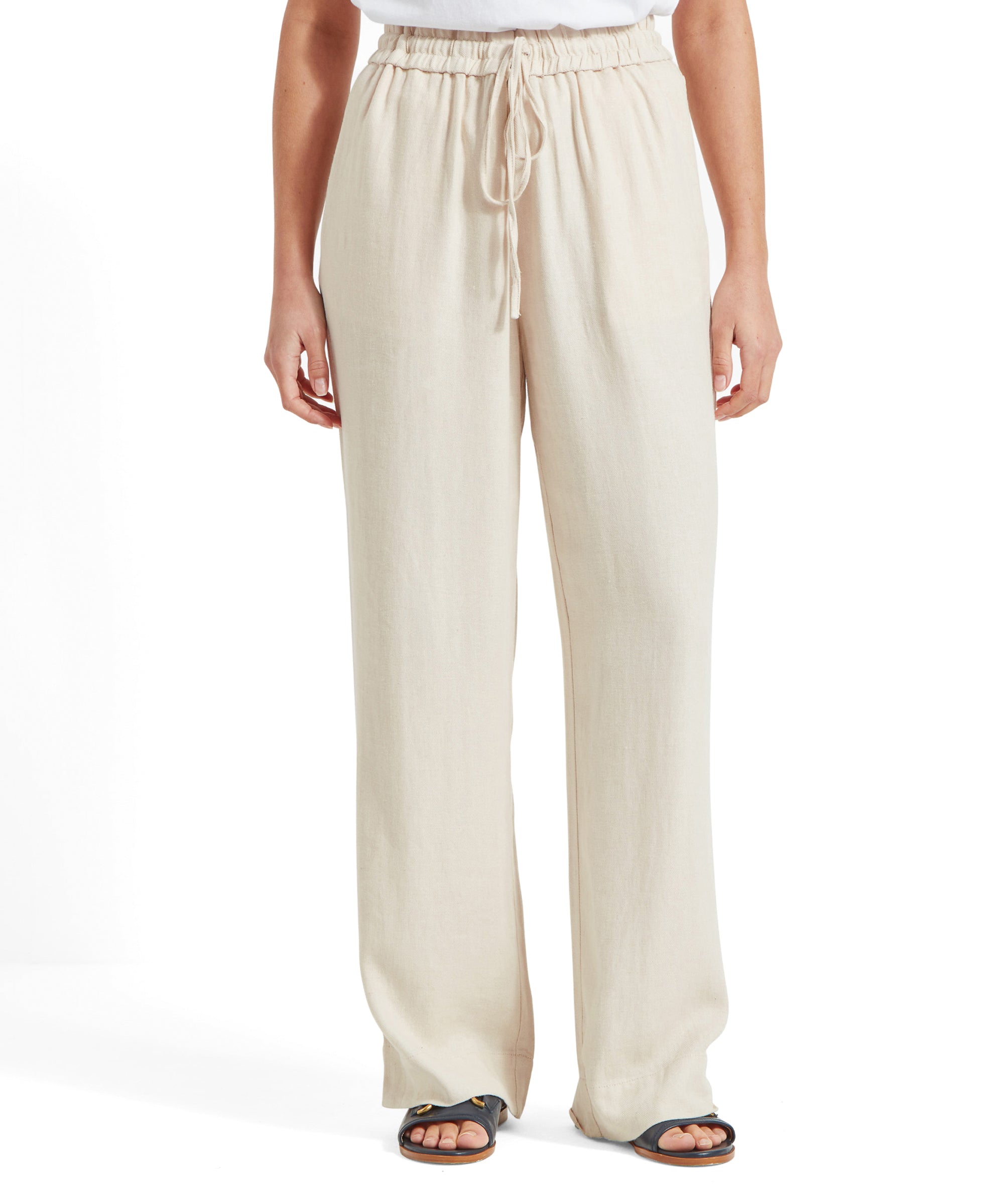 Front view of light brown, wide-leg trousers with an elastic drawstring waist, worn by a model with sandals.