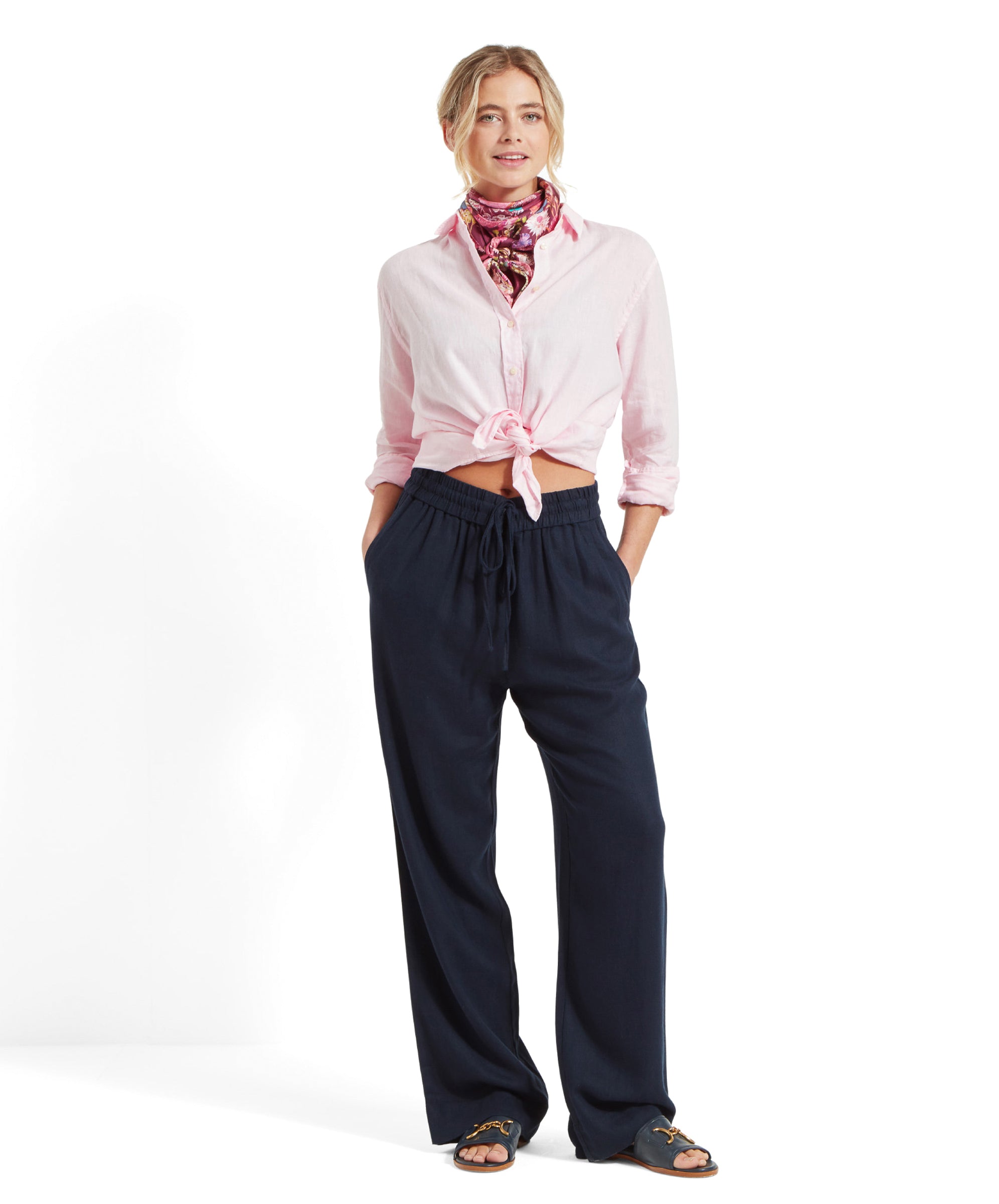 Full body shot of a woman wearing Schöffel Women's Daphne Trousers in navy, paired with a pink shirt and a colorful neck scarf.