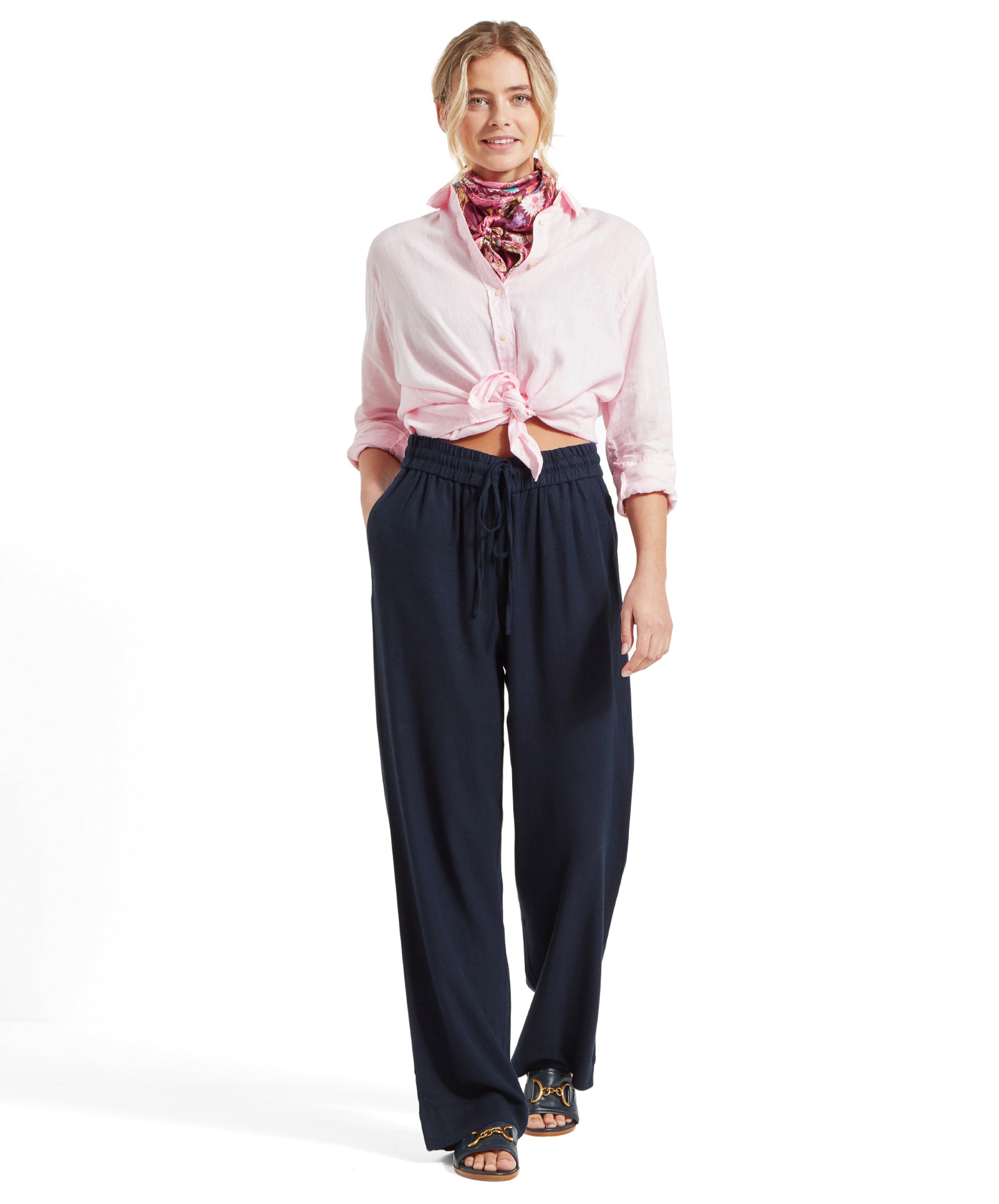 Full body shot of a woman wearing Schöffel Women's Daphne Trousers in navy, paired with a pink shirt and a colorful neck scarf.