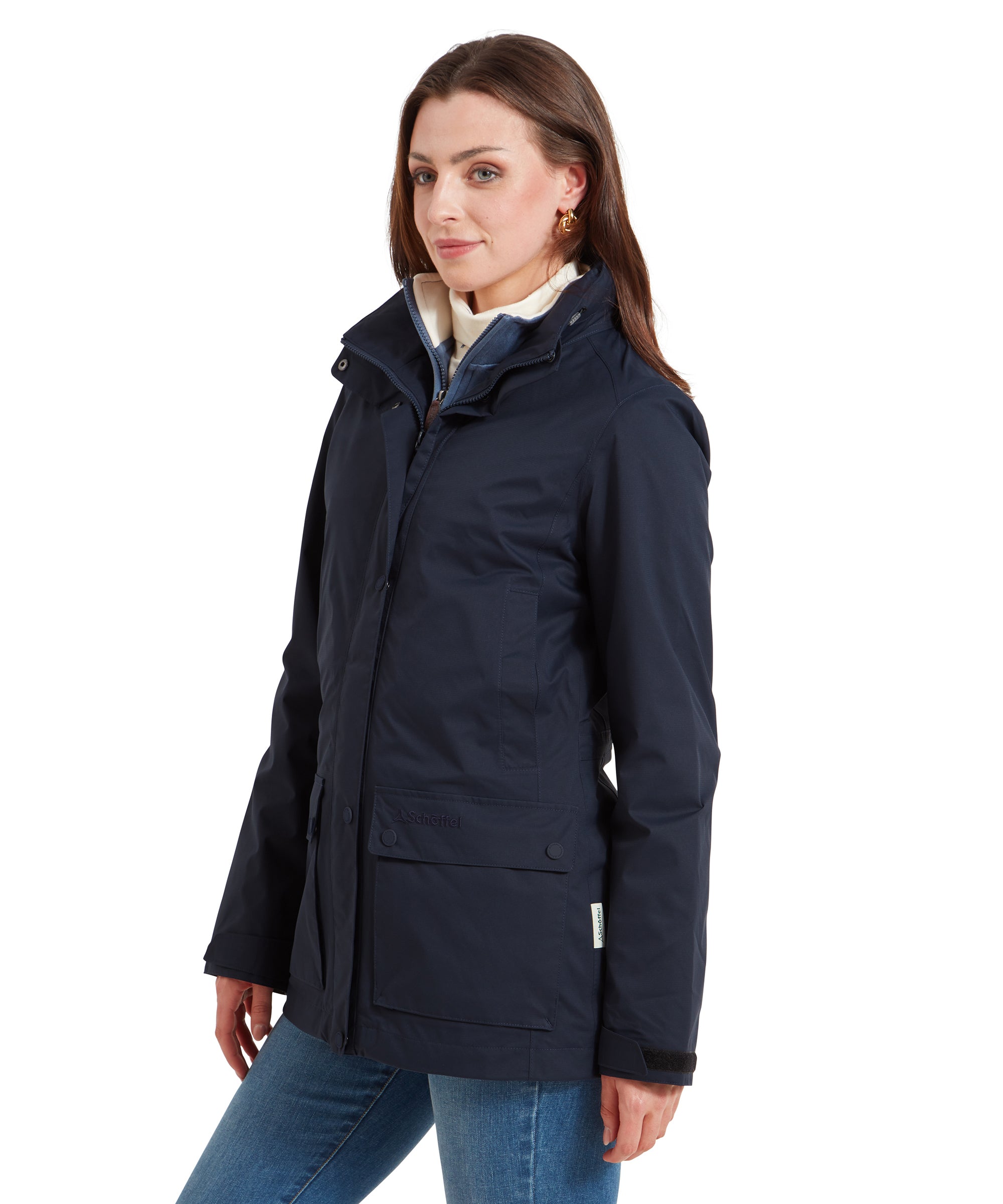 A woman is seen from the side, wearing a Schöffel Edith Jacket for Women in Blue with a front zip and button closure. The jacket is fitted at the waist, with a slightly raised collar.