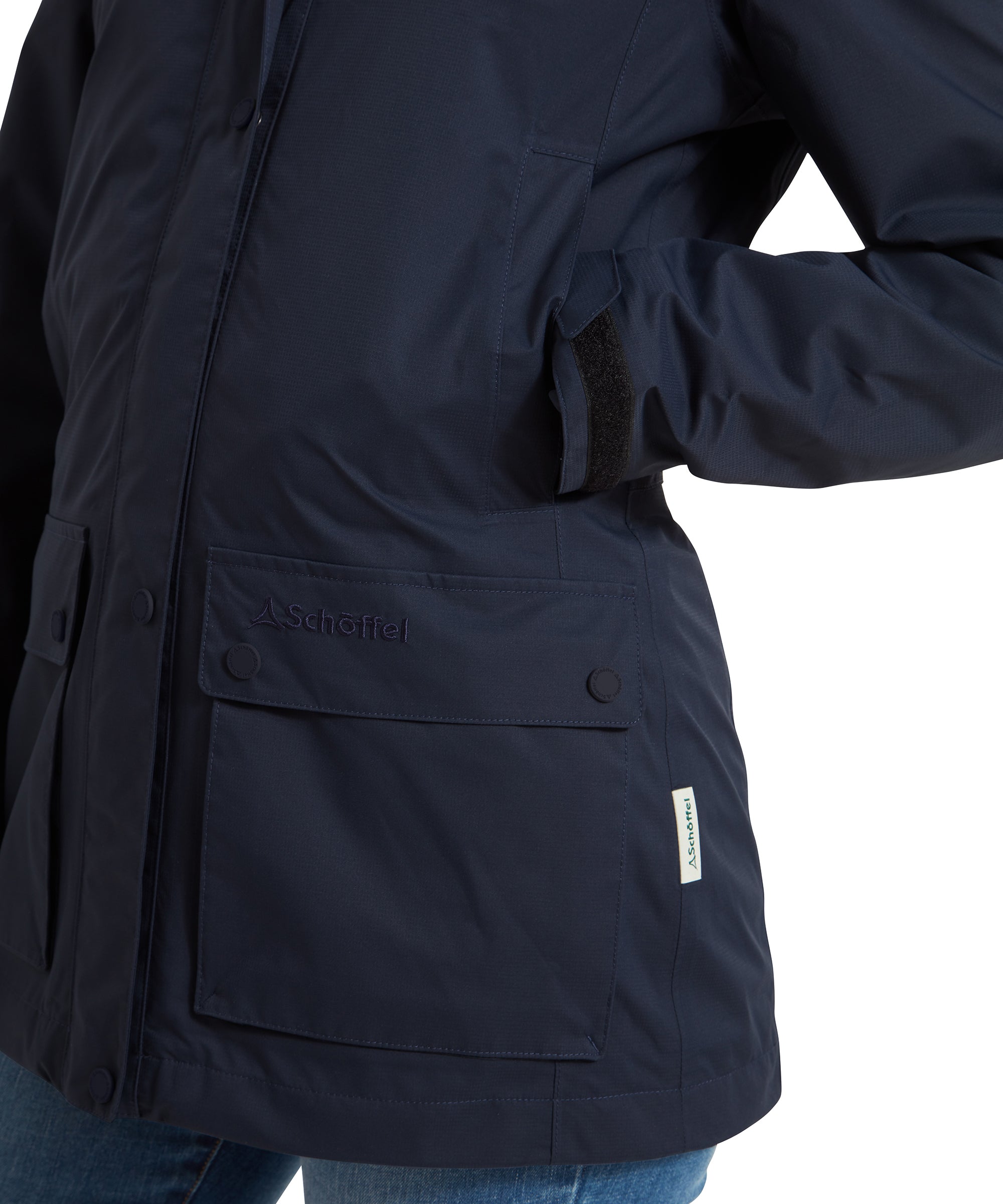 A close-up of the front pocket on a Schöffel Edith Jacket for Women in Blue, showcasing the buttoned flap pocket with "Schöffel" branding on the pocket.