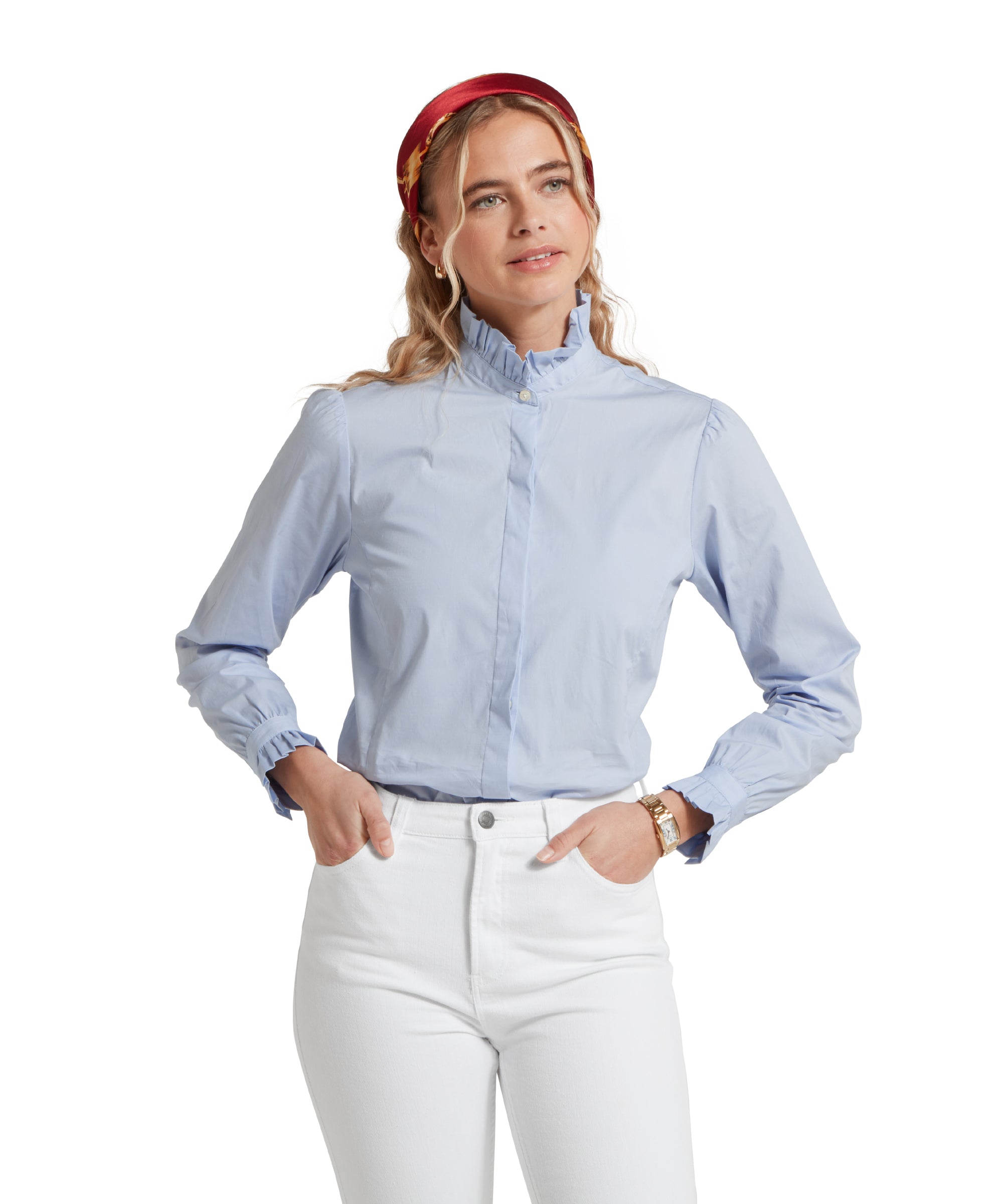 Close-up of a female model wearing a light blue Schöffel shirt, paired with white jeans. She is standing in a relaxed pose with her hands in her pockets.