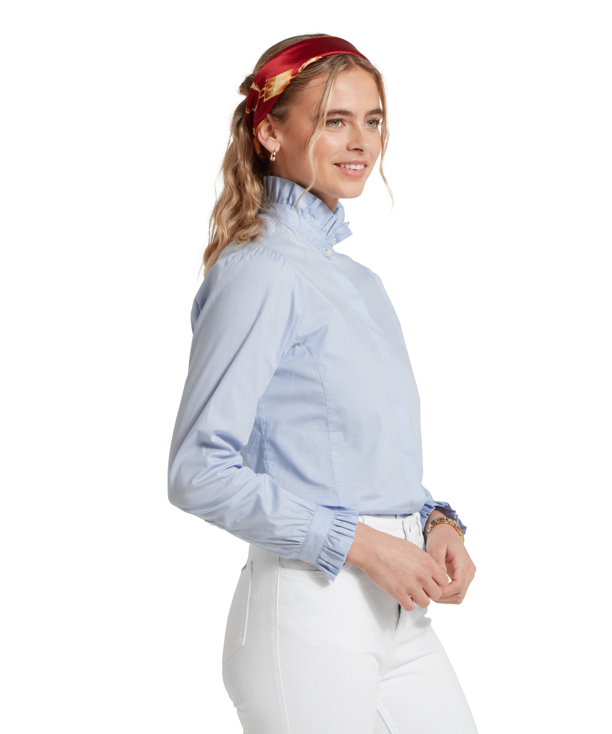 Side profile of a female model wearing a tucked in light blue Schöffel shirt, paired with white jeans.