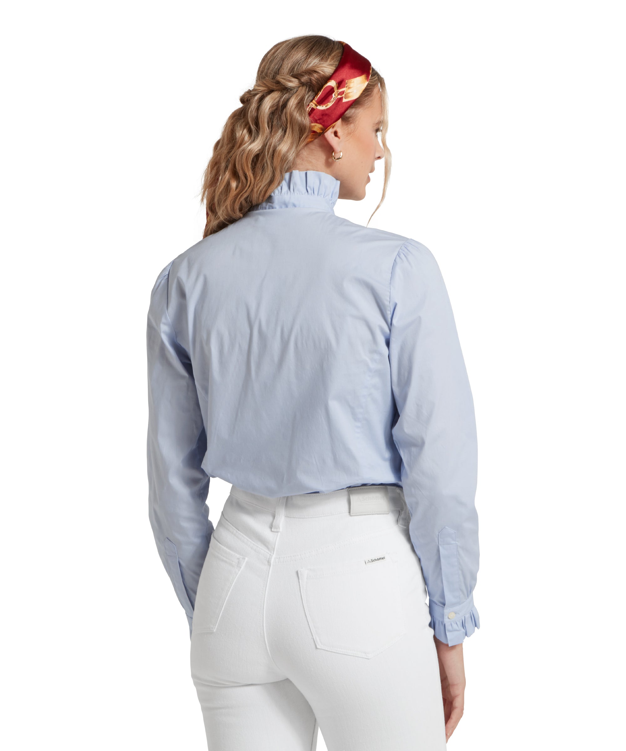 Back image of a female model wearing a light blue Schöffel shirt, tucked into a pair of white jeans. She is standing in a relaxed pose with her hands at her side.