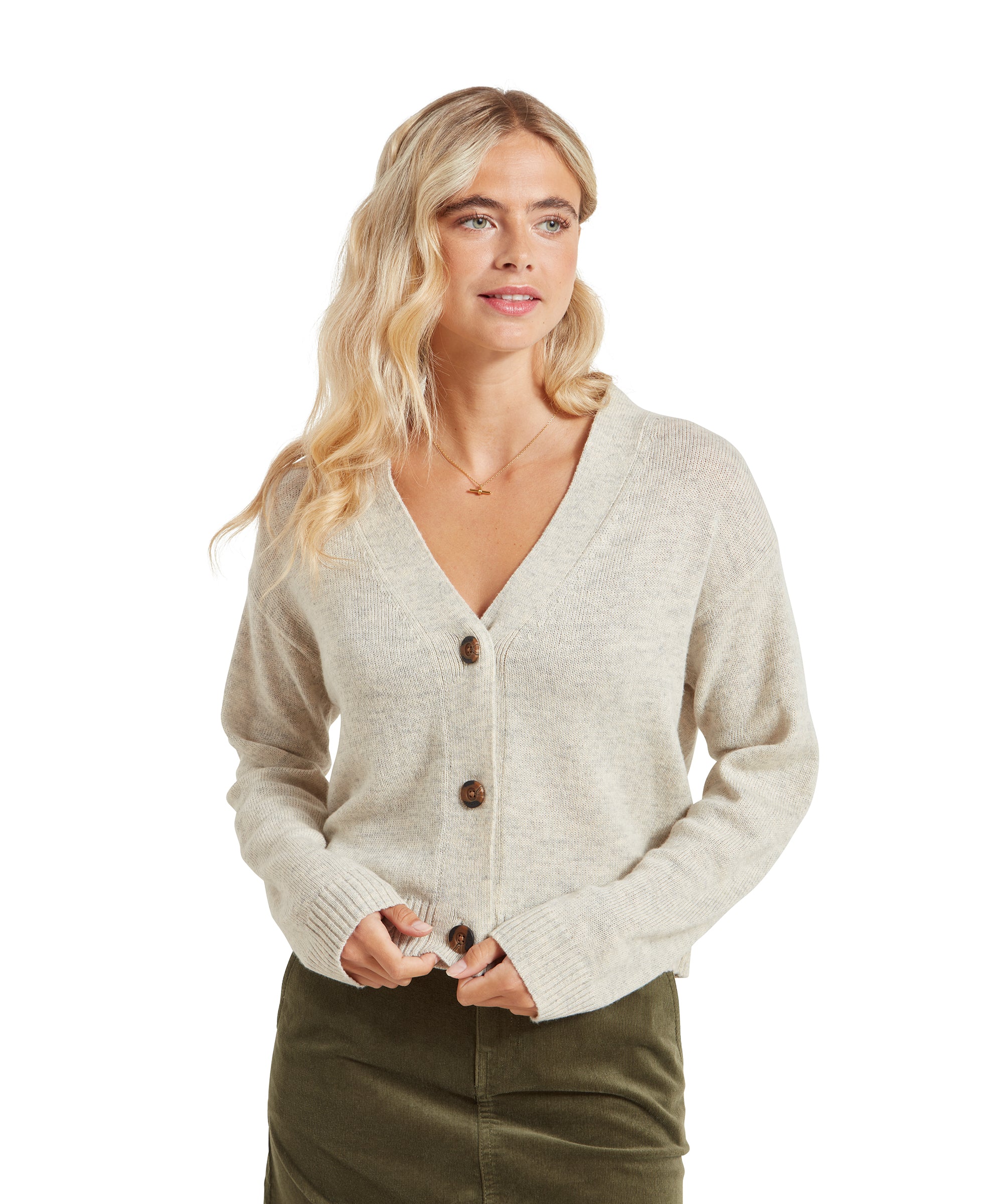 A woman is wearing a Schöffel Filey Cardigan for Women in Beige with three large buttons down the front. She has blonde wavy hair and is smiling slightly. The cardigan is paired with an olive green skirt.