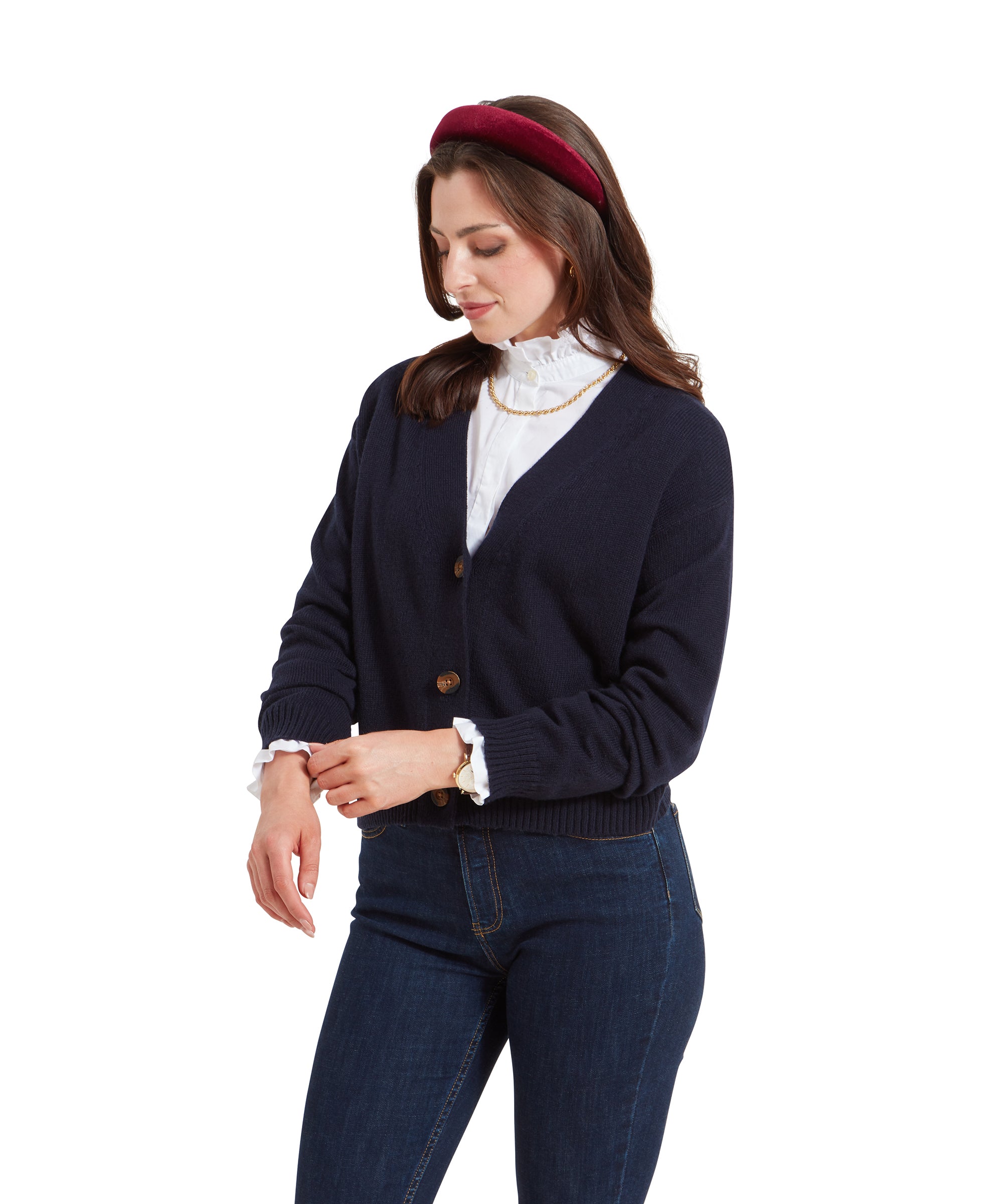 Side view of the woman in the Schöffel Filey Cardigan for Women in Navy and jeans, adjusting her sleeve with a soft smile.