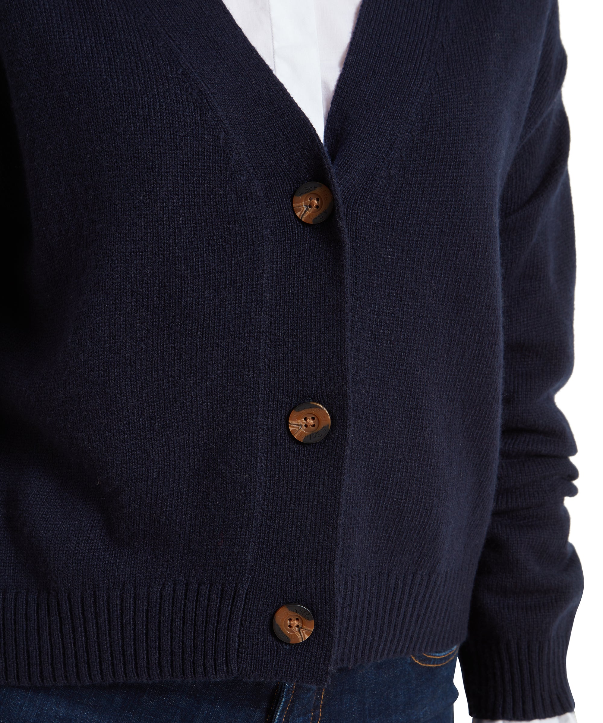 A close-up of the Schöffel Filey Cardigan for Women in Navy, focusing on the brown buttons and the fine knit texture, with a portion of the white ruffled shirt visible underneath.