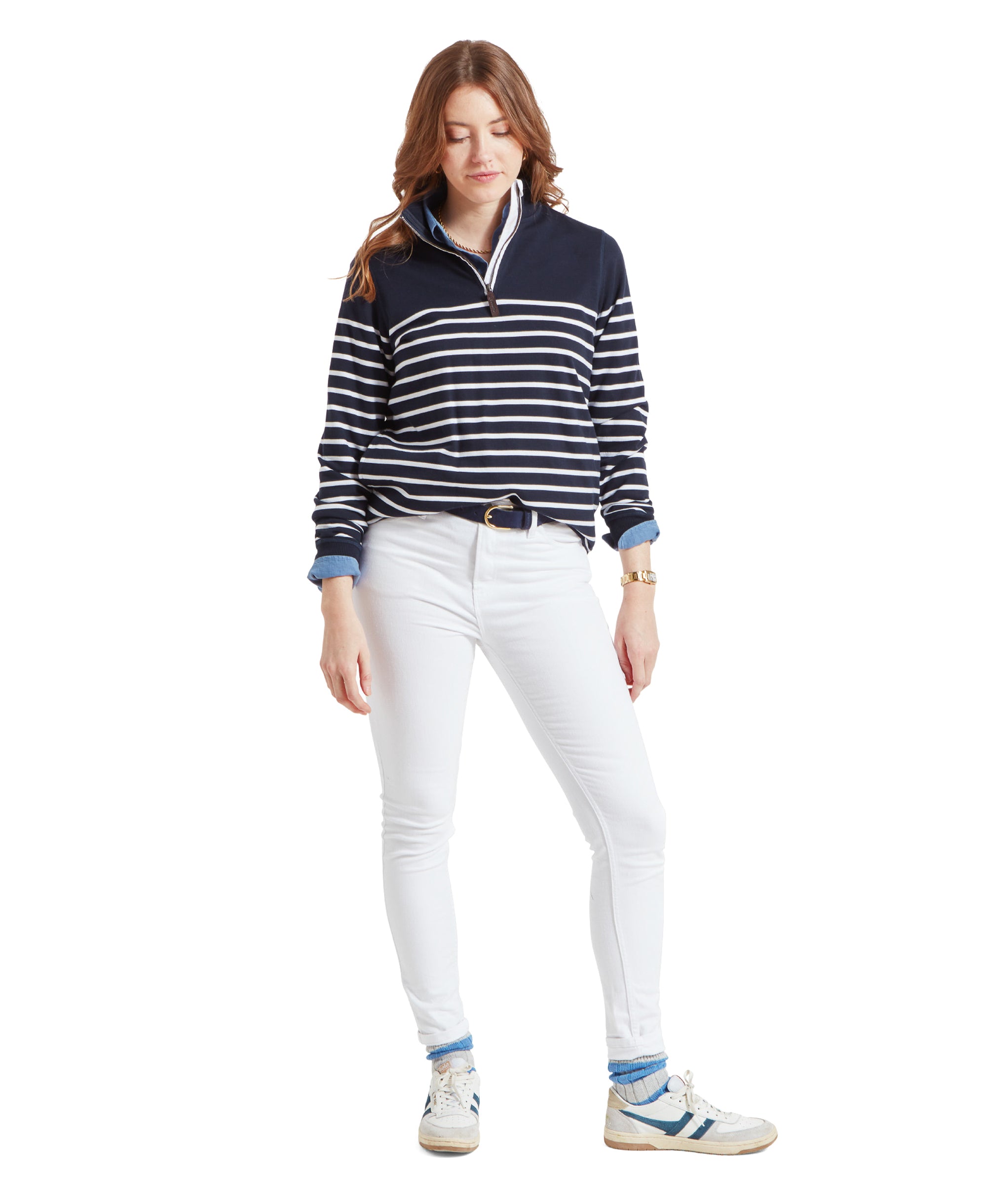 Full body shot of a woman in a Schöffel Hope Cove Sweatshirt for Women in Navy, white jeans, and trainers, standing and looking down.