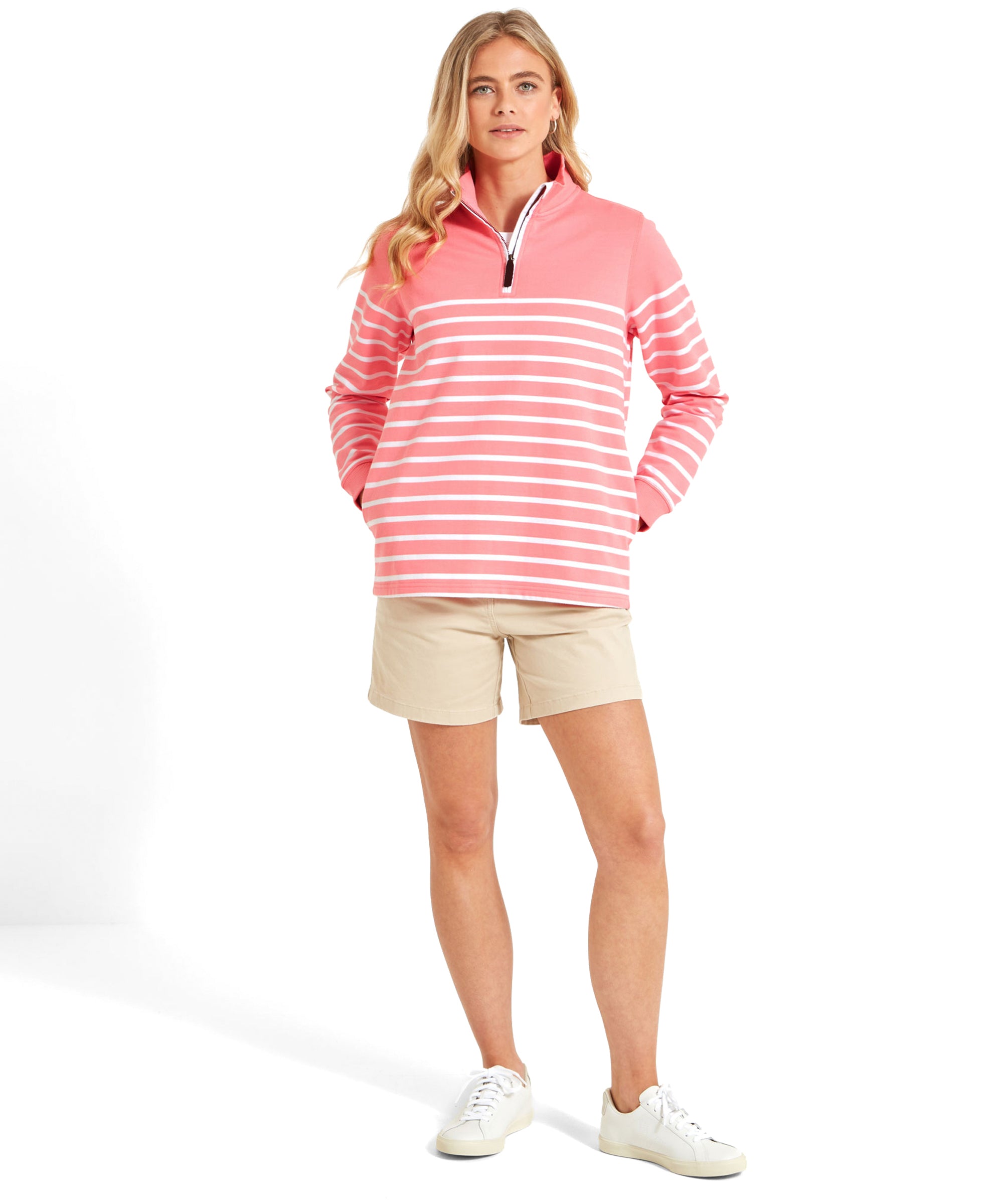 A woman standing in a Schöffel Hope Cove Sweatshirt for Women in Pinkand beige shorts, with hands in pockets and looking at the camera.