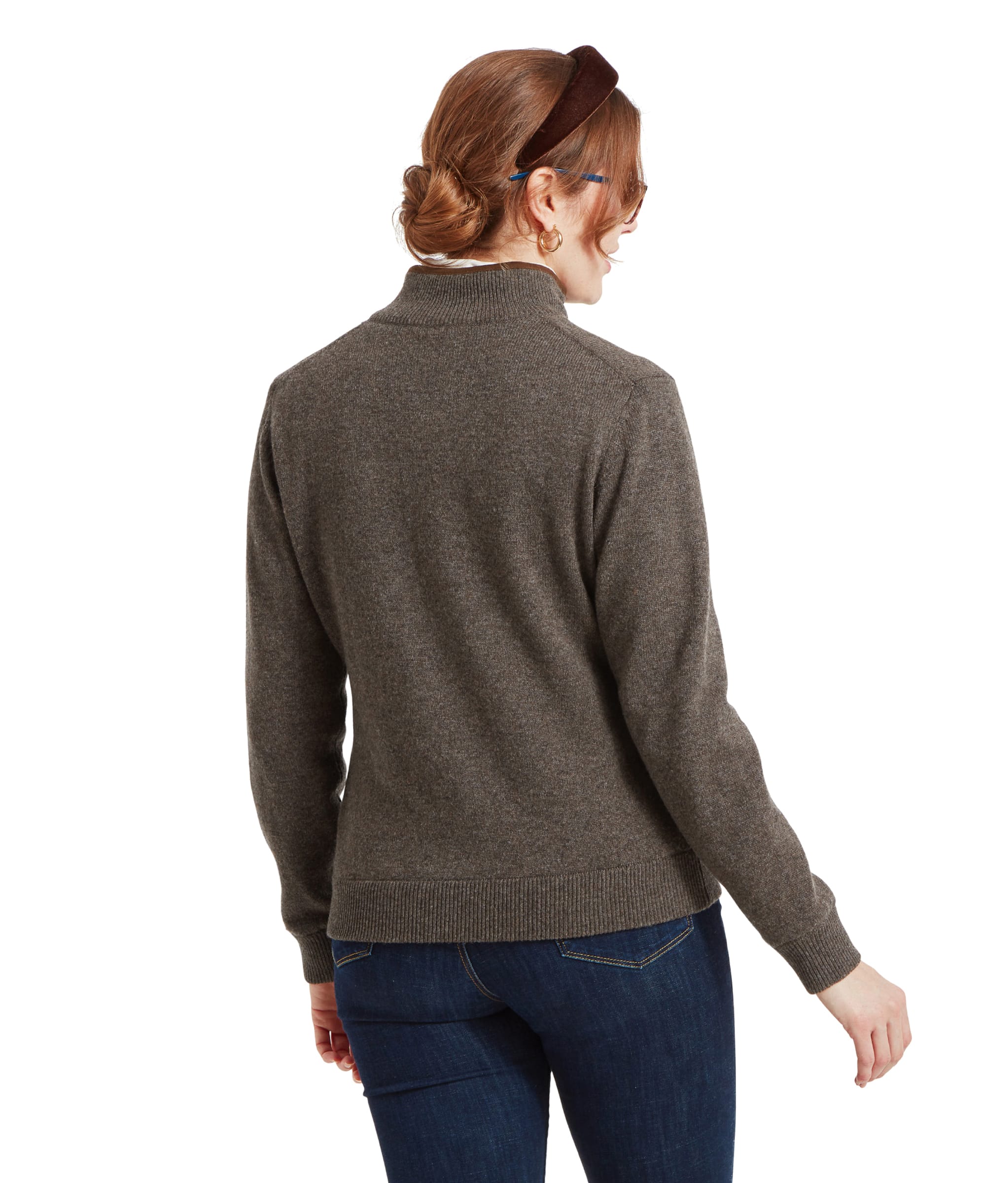 A rear view of a woman wearing a Schöffel Women's Lambswool Aerobloc 1/4 Zip for Womens in Brown and dark blue jeans. Her hair is styled in a low bun with a brown headband.