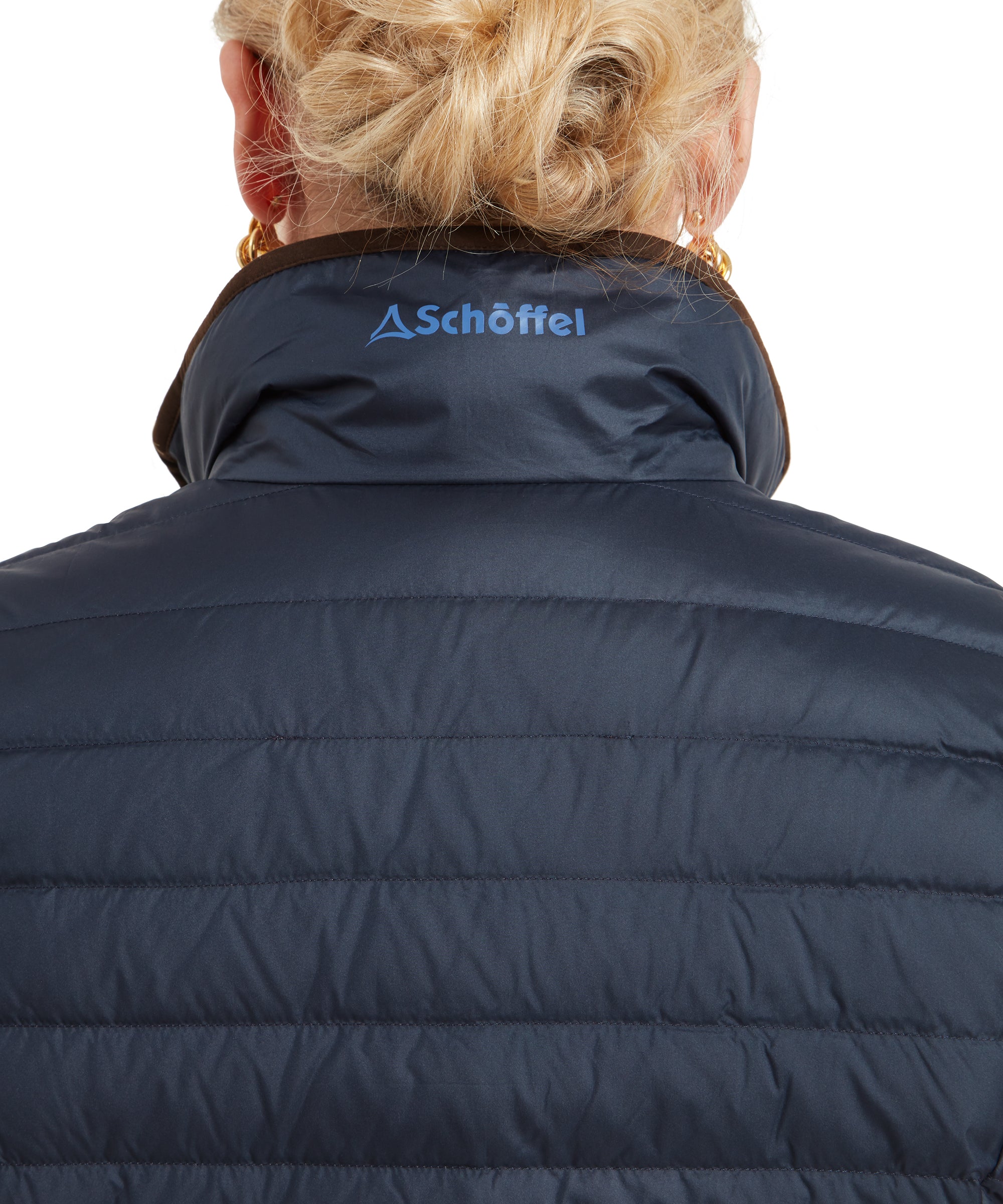 A close-up of the Schöffel Launde Down Gilet for Women in Navy’s collar from the back, showing the embroidered Schöffel logo in blue.