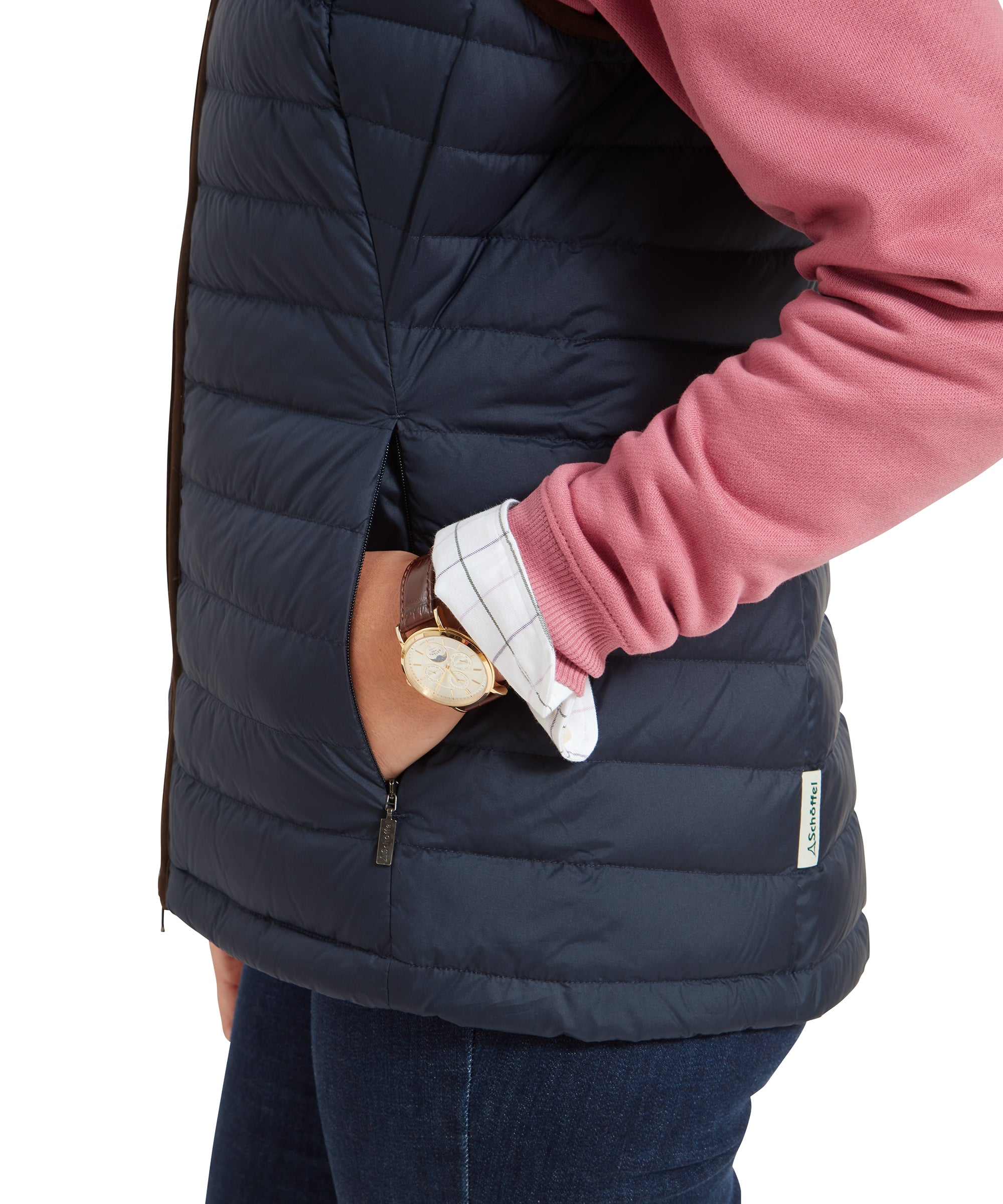 A close-up of the woman’s hand in the pocket of the Schöffel Launde Down Gilet for Women in Navy, highlighting the brown trim and zipper detail.