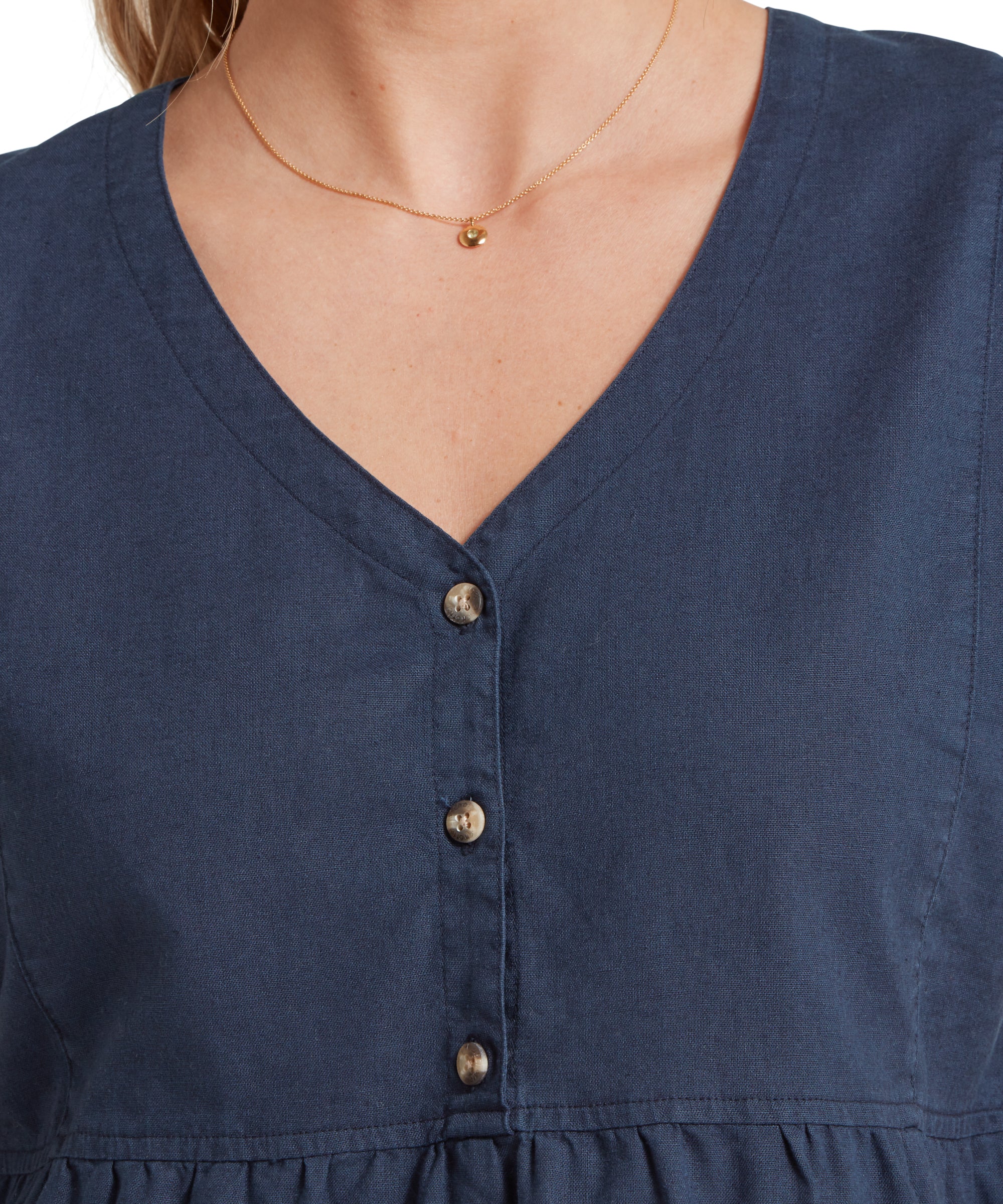 Close up image of a female model wearing a v-neck navy linen Schöffel top paired with gold accessories. Image highlights v neck and buttoned front.