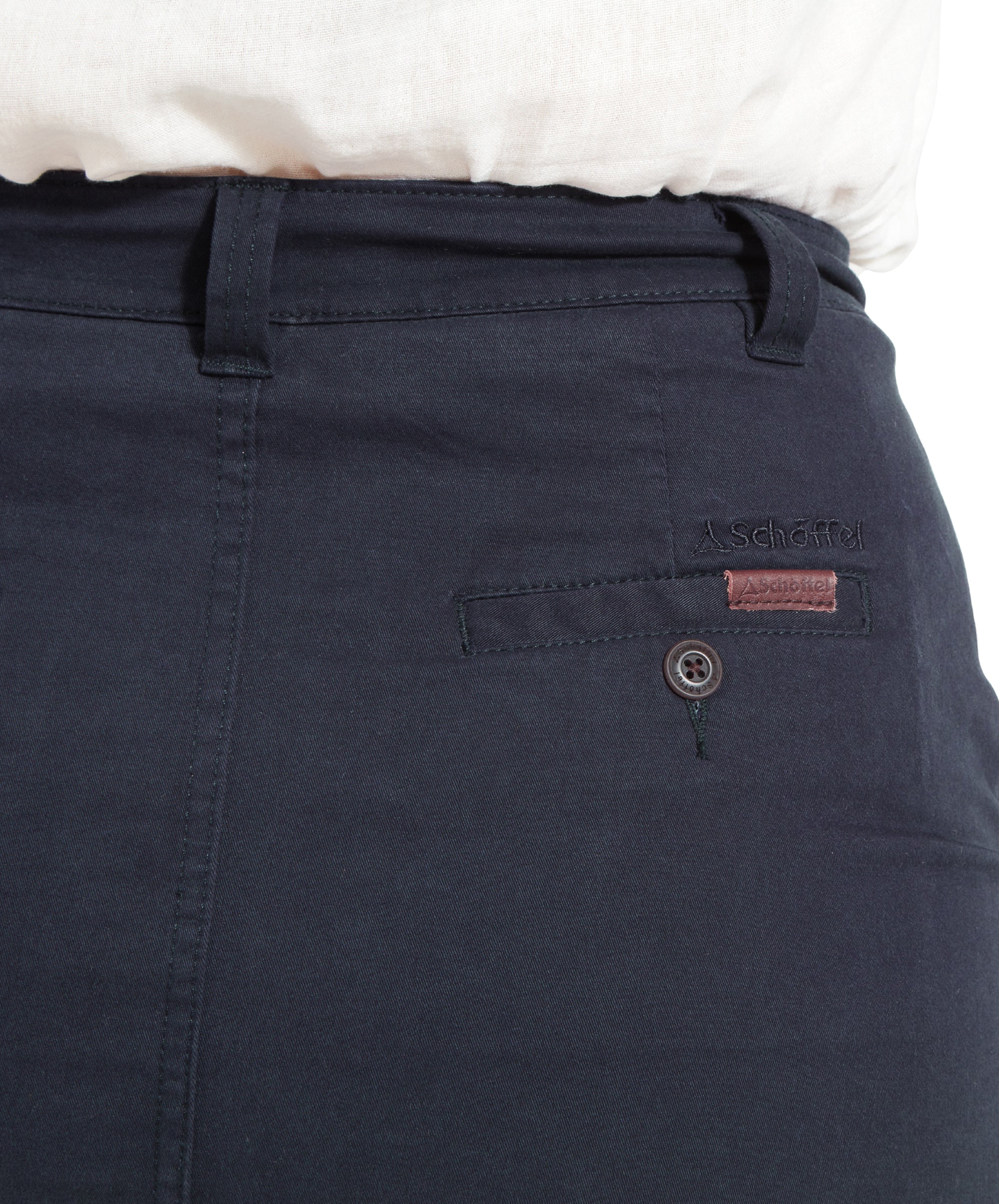 A close-up of the back pocket of the Schöffel Lily Skirt for Women in Navy. The skirt has a small "Schöffel" label above the pocket and is worn with a white shirt.