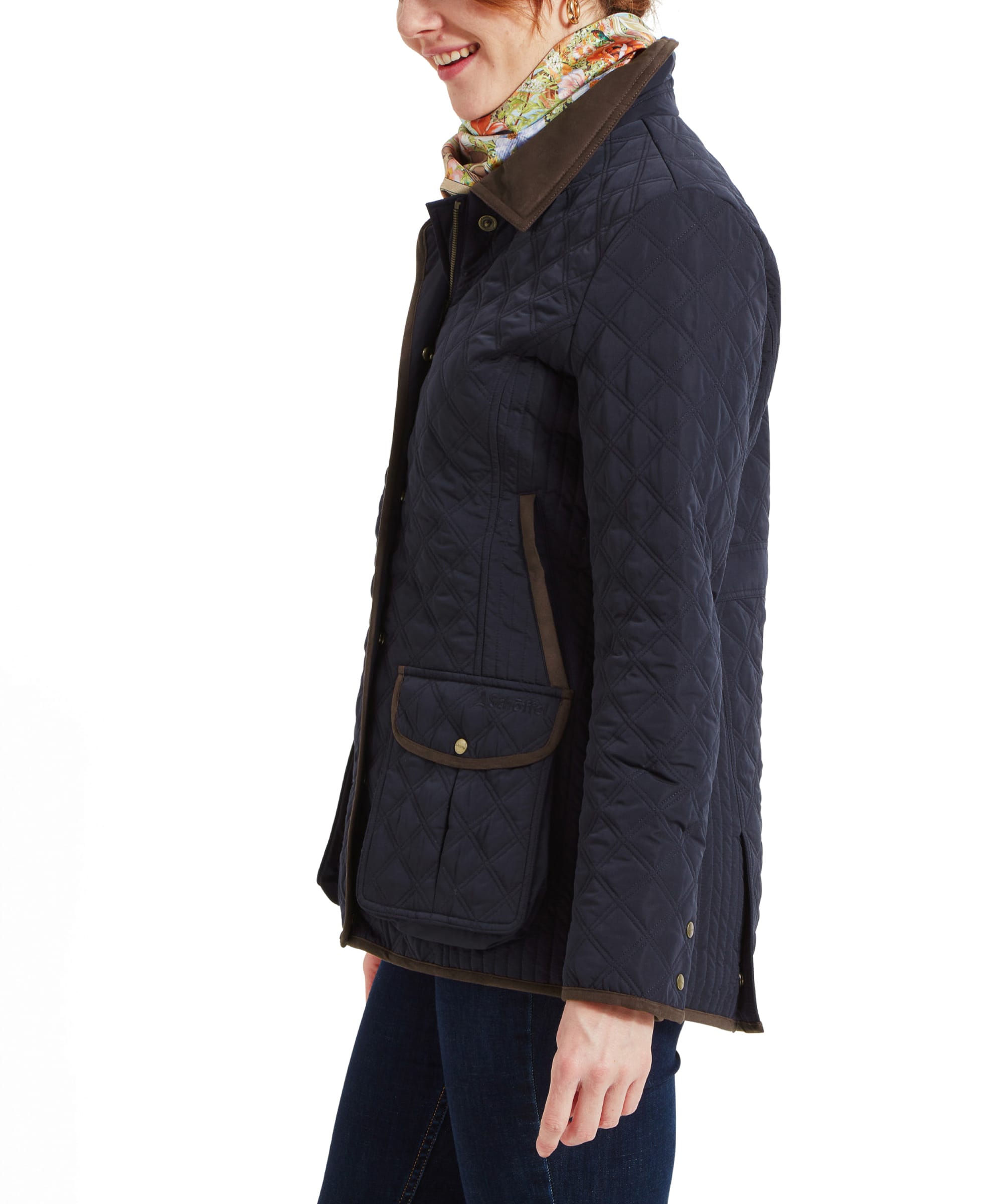 Side profile of the woman in the Schöffel Lilymere Quilted Jacket for Women in Blue, showing the fit and detailing along the side of the jacket, including the brown trim on the pockets.