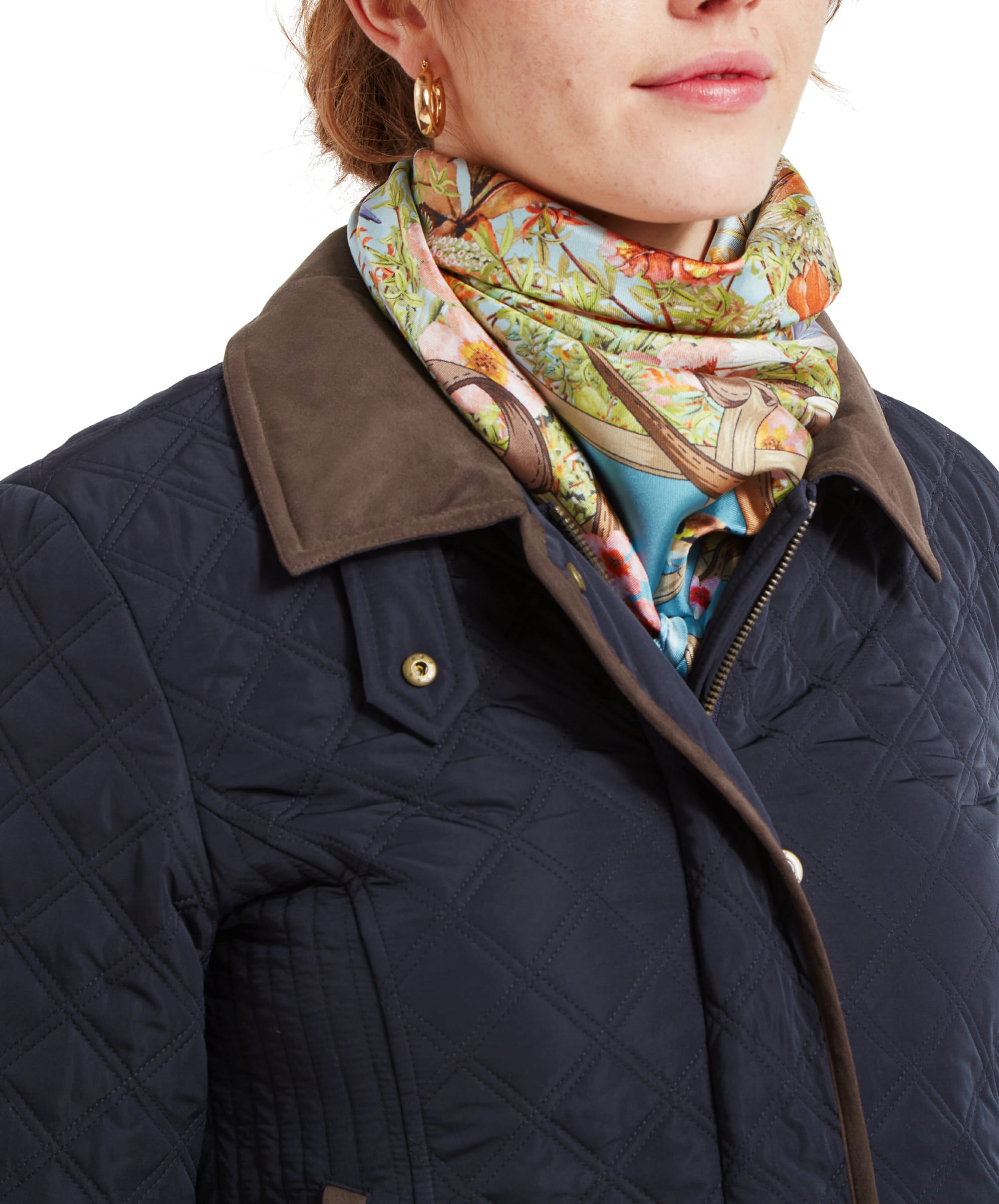 Close-up of the woman's upper body, focusing on the collar, scarf, and top portion of the Schöffel Lilymere Quilted Jacket for Women in Blue. The brown collar contrasts with the patterned scarf.