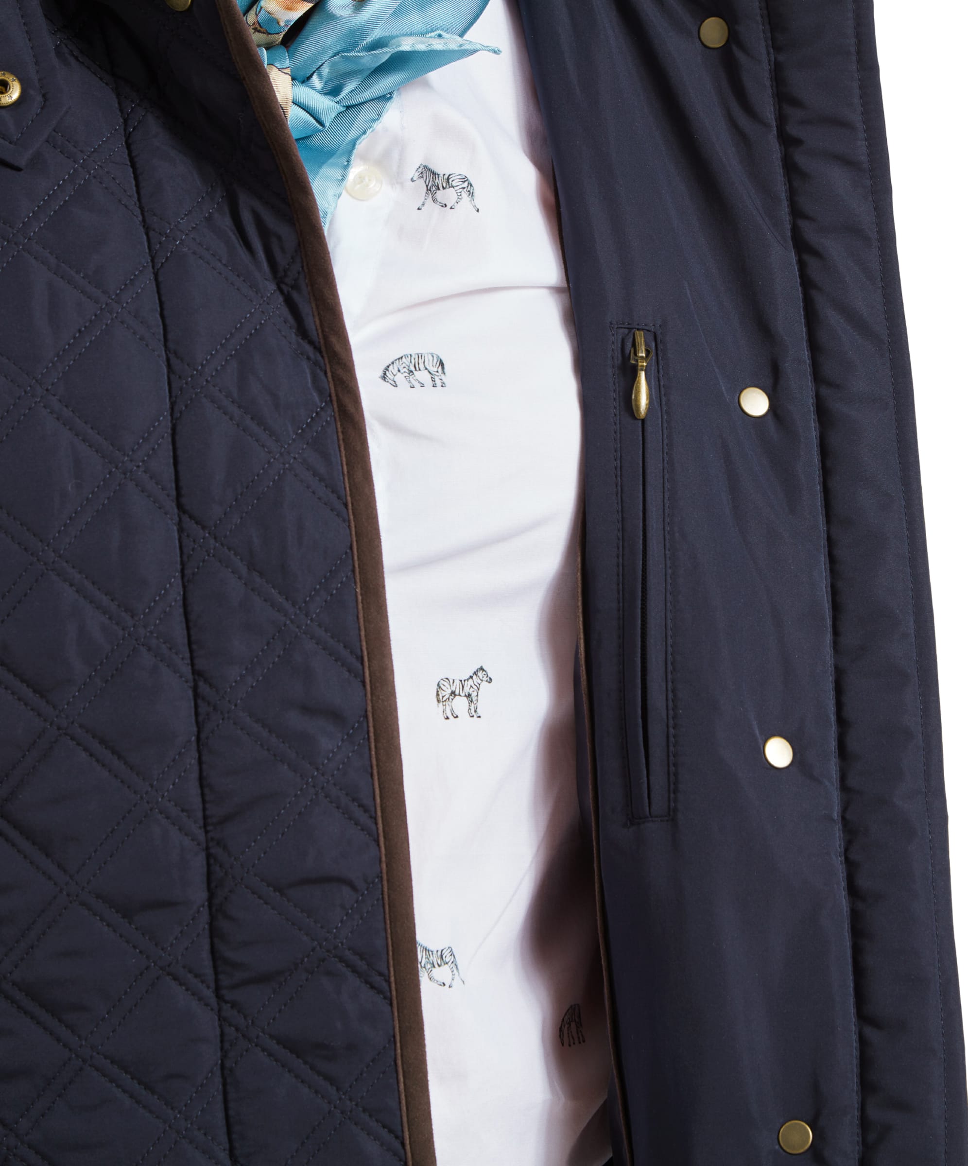 Inside view of the Schöffel Lilymere Quilted Jacket for Women in Blue, showing a zippered inner pocket and the patterned shirt the woman is wearing underneath.