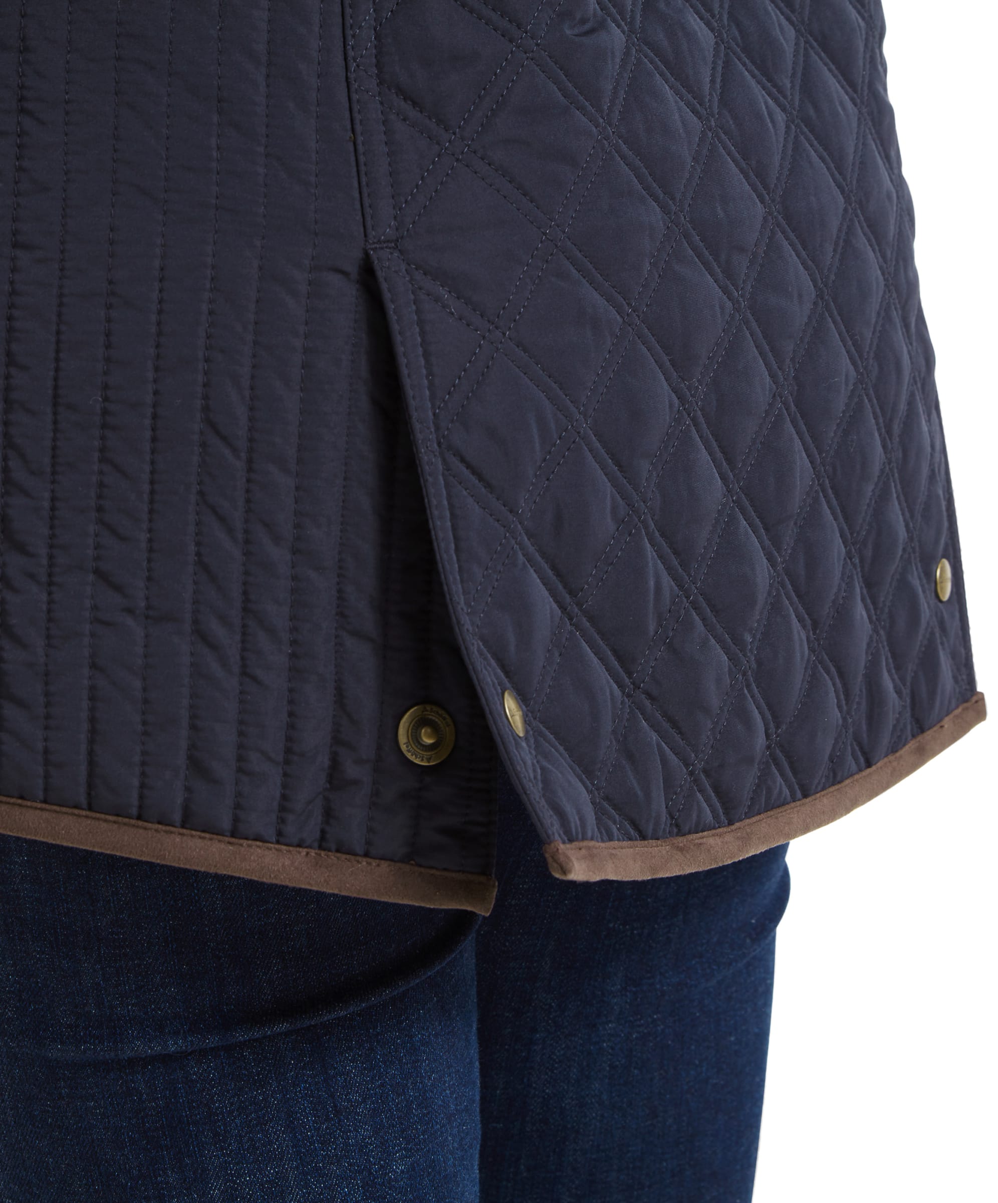 Detail of the Schöffel Lilymere Quilted Jacket for Women in Blue's lower back, showing the buttoned side vent and brown trim along the hem.