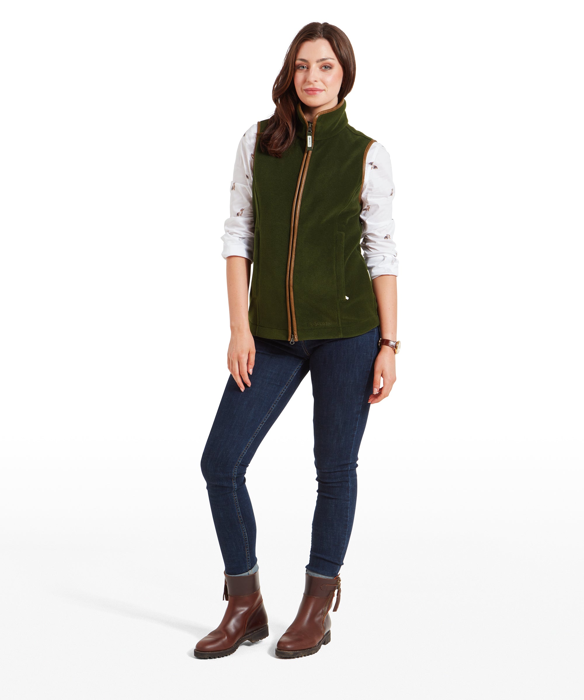 Full-body view of the woman wearing the Schöffel Lyndon Fleece Gilet for Women in Olive Green. She stands with a relaxed posture, hands in pockets, wearing dark jeans and brown ankle boots.