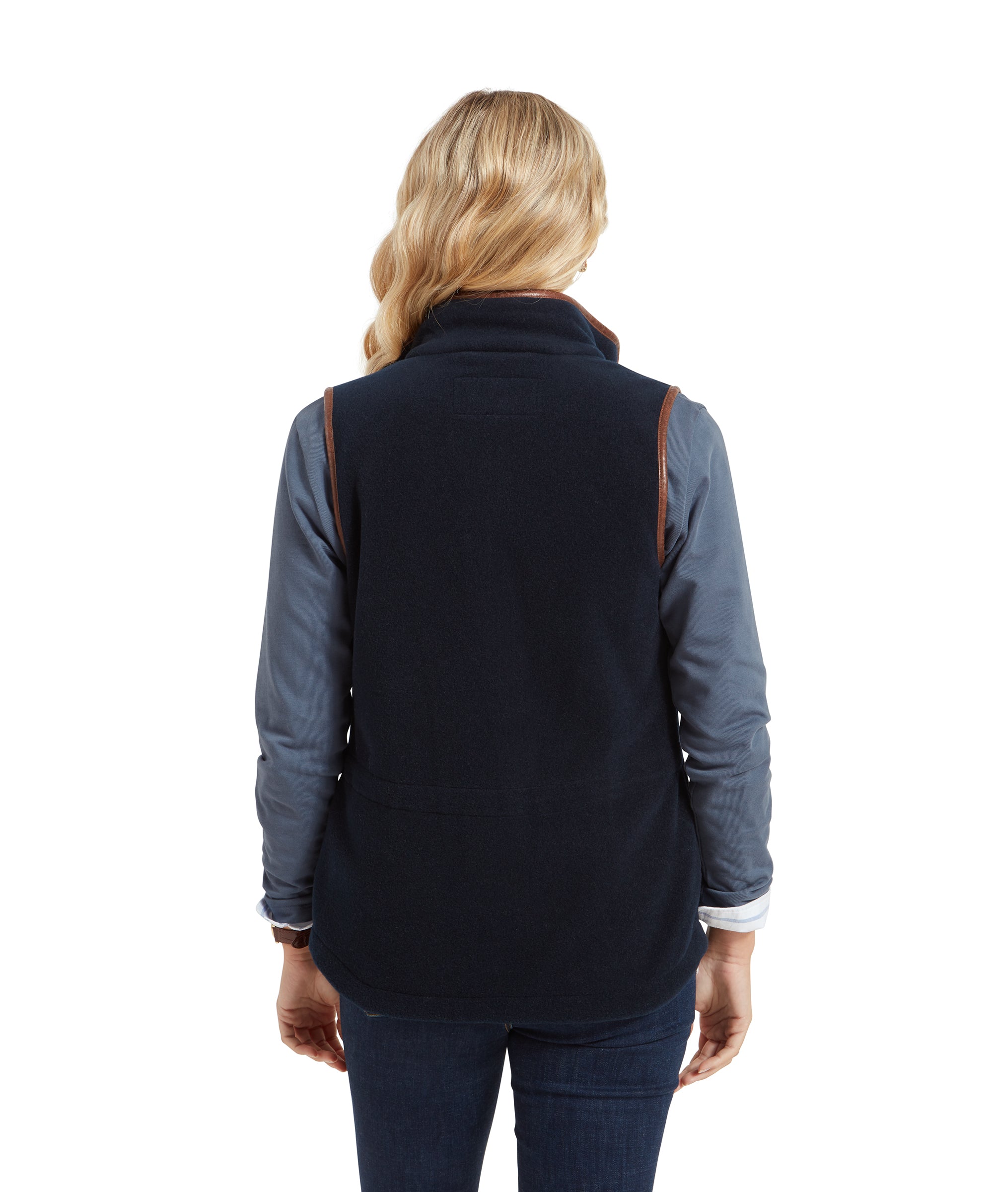 The woman is turned away from the camera, providing a clear view of the back of the Schöffel Lyndon Fleece Gilet for Women in Navy. The fitted style of the gilet is highlighted, showing how it cinches slightly at the waist for a tailored fit.