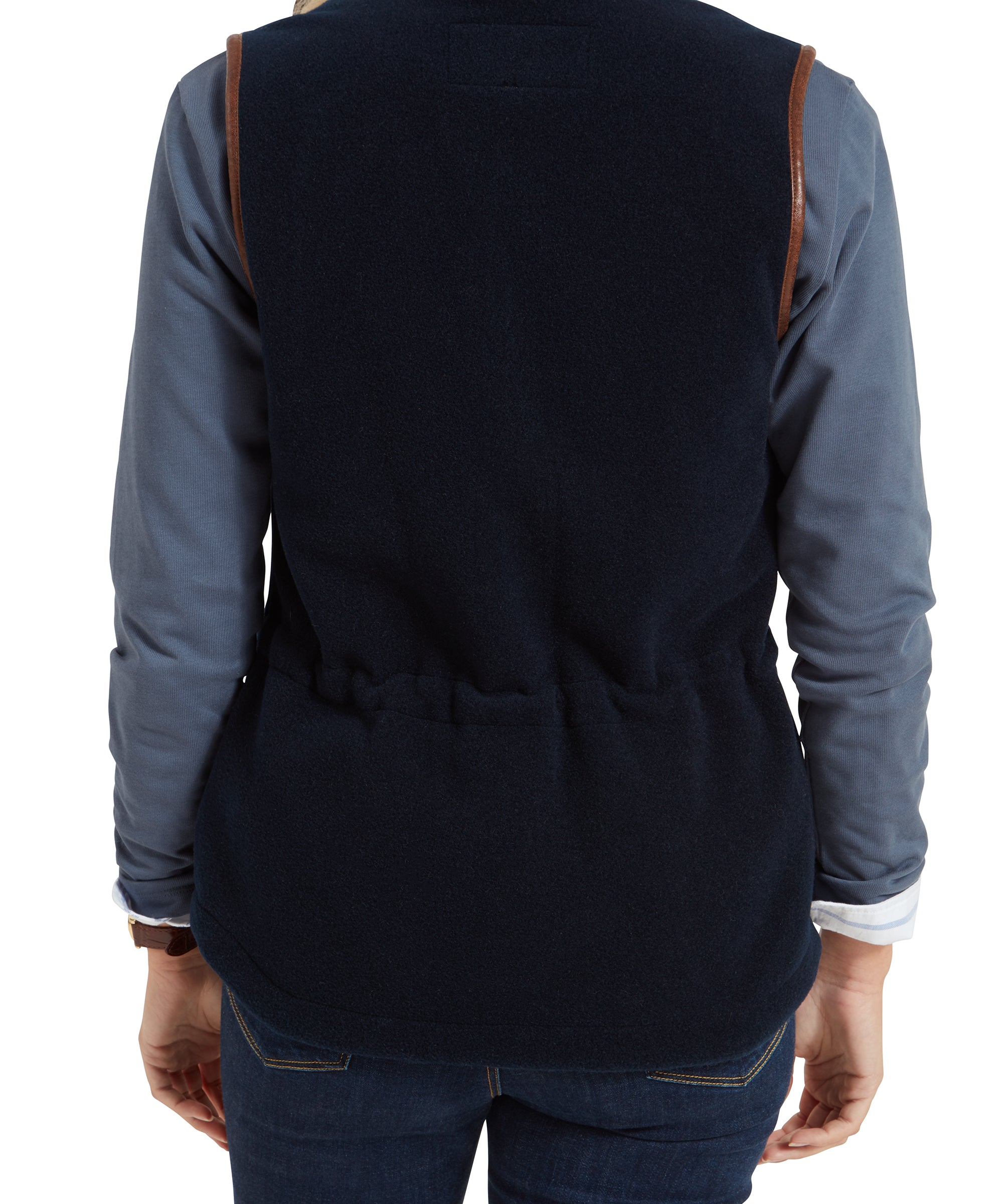 A rear view of the woman, showing the back of the Schöffel Lyndon Fleece Gilet for Women in Navy with an adjustable waist and brown trim details on the armholes.