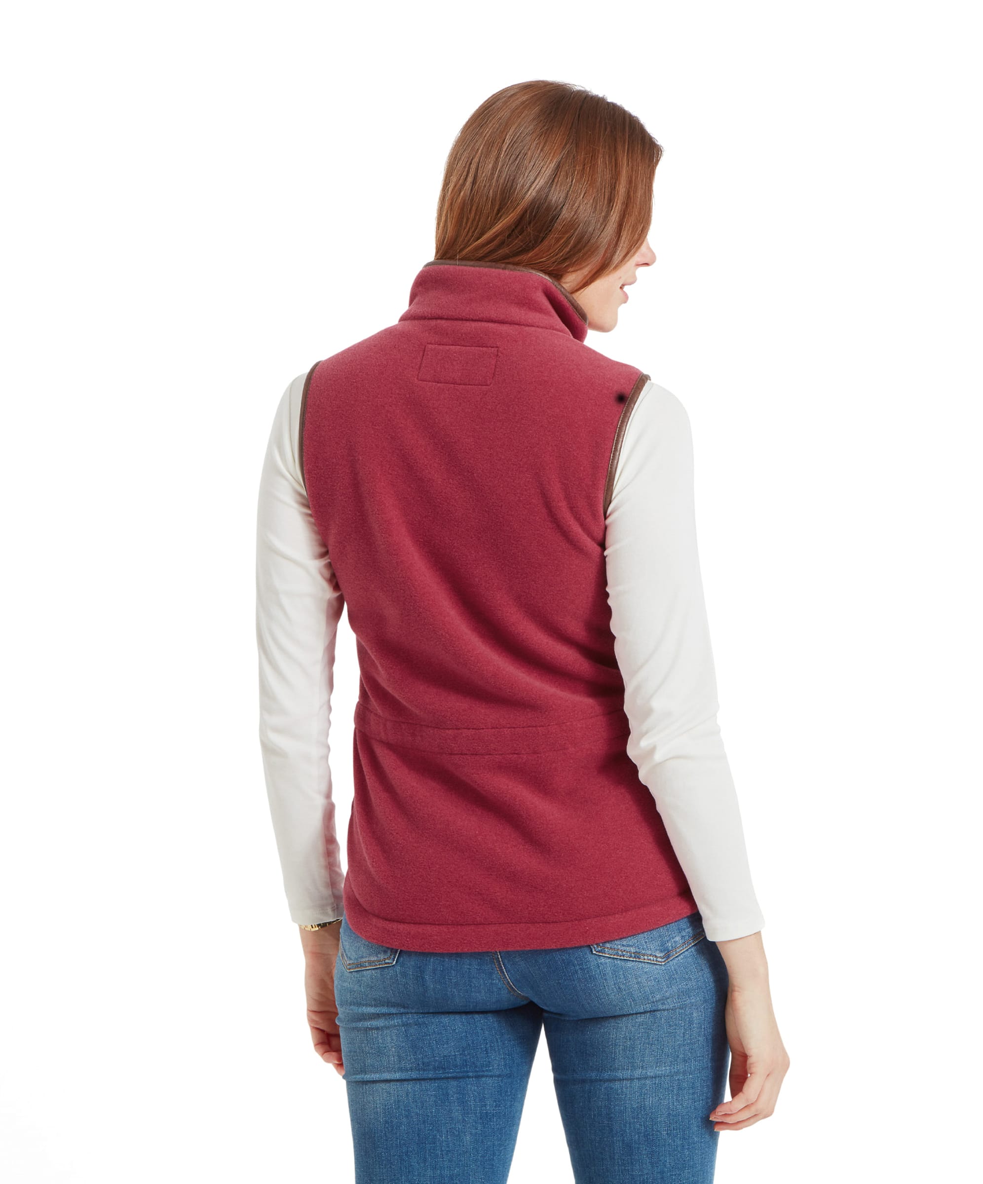 A back view of the Schöffel Lyndon Fleece Gilet for Women in Red, showing the gathered waist detail. The model's hair is down, and she is wearing a white turtleneck and blue jeans.