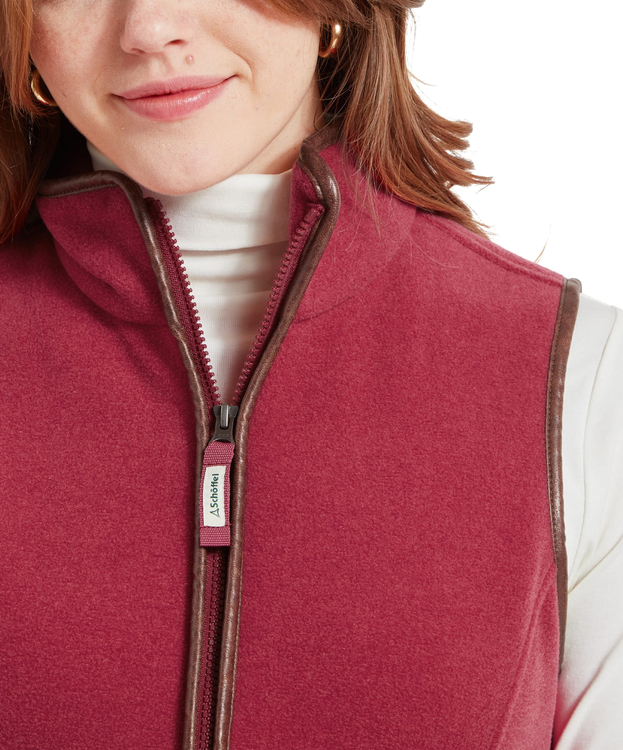 A close-up of the Schöffel Lyndon Fleece Gilet for Women in Red, focusing on the front zipper and high collar. The model is wearing a white turtleneck.