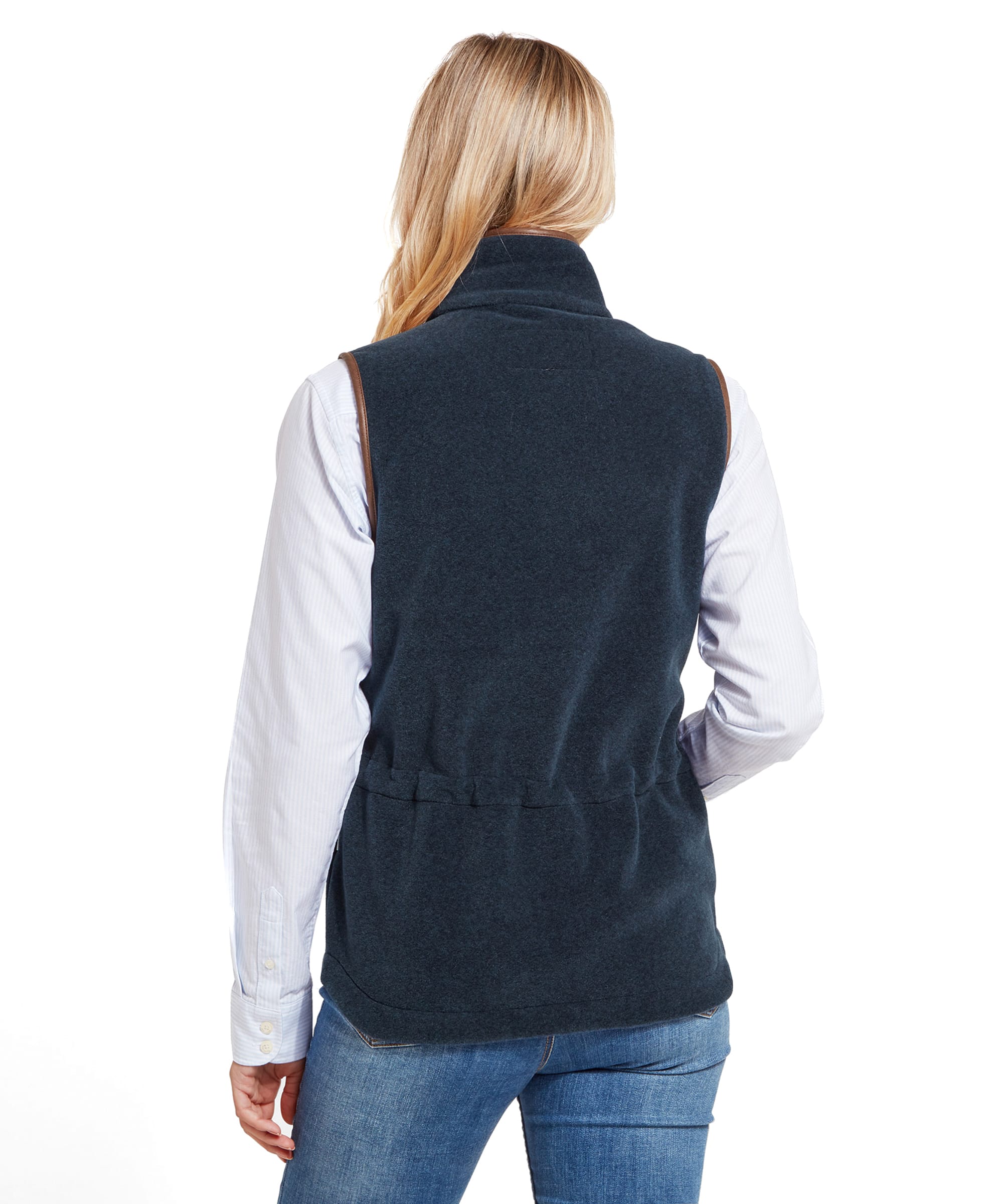 The back view of the woman shows the Schöffel Lyndon Fleece Gilet for Women in Navy Blue fitting snugly around her waist with gathered elastic detailing, still paired with the light blue shirt and blue jeans.