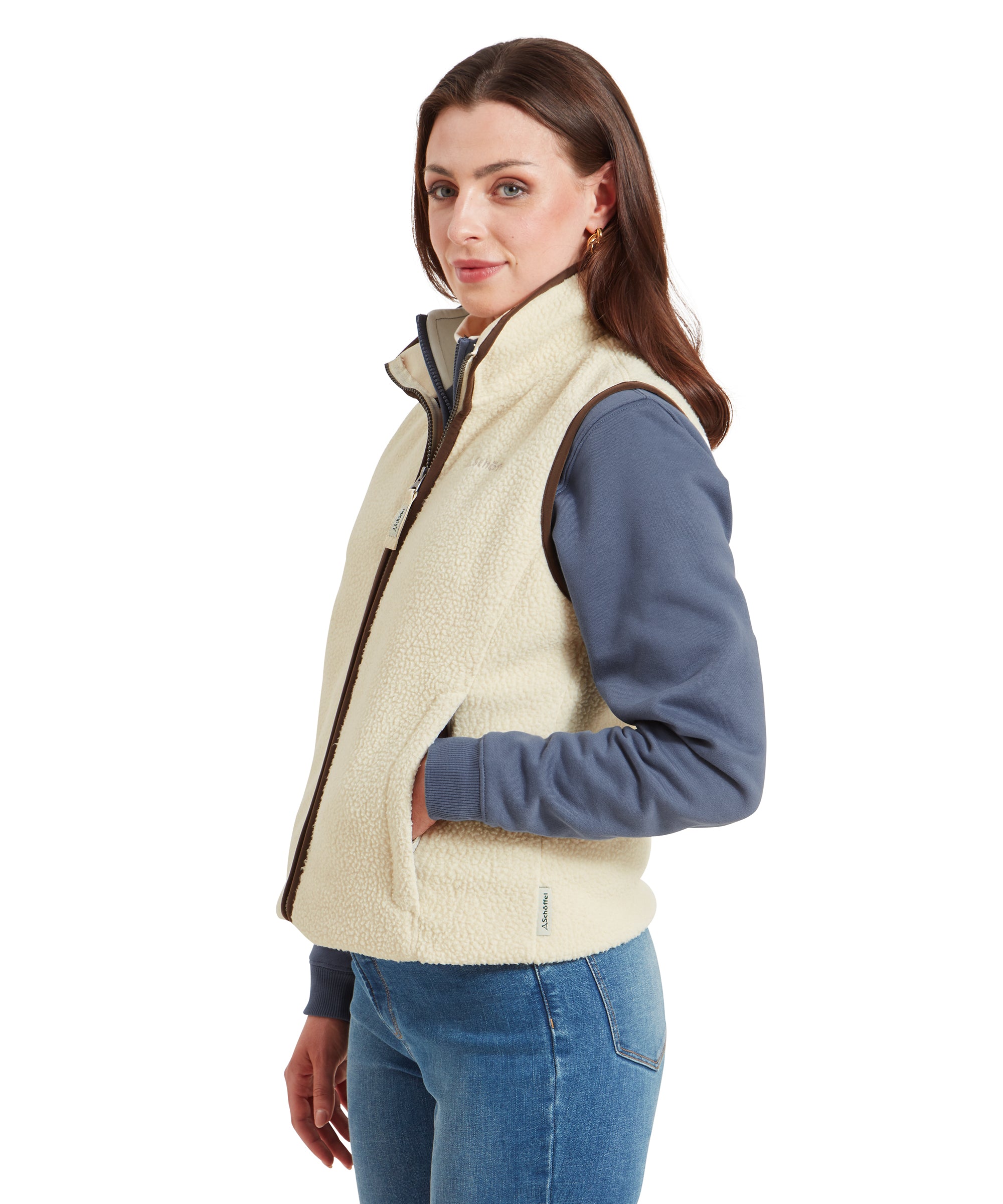 A side view of the woman wearing the Schöffel Lyndon Retro Fleece Gilet for Women in Cream, showing her right side as she looks toward the camera.