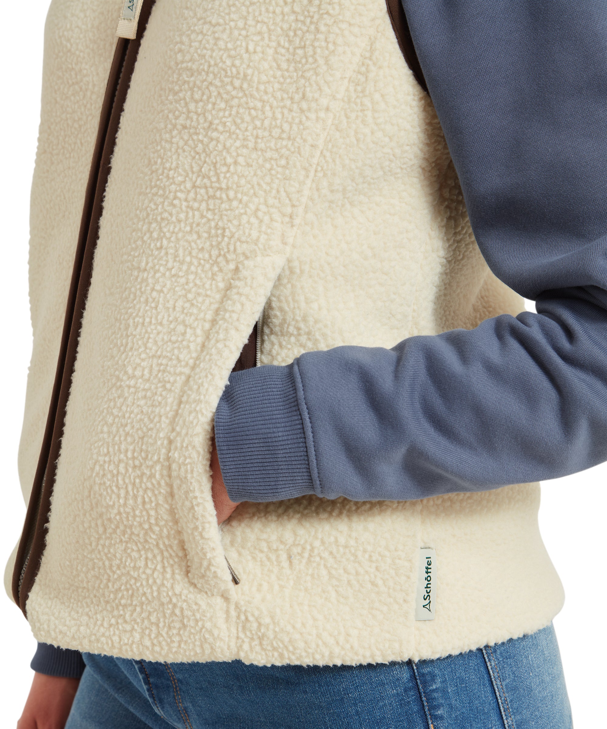 A close-up view of the woman’s hand resting in the pocket of the Schöffel Lyndon Retro Fleece Gilet for Women in Cream, emphasizing the texture and stitching detail.