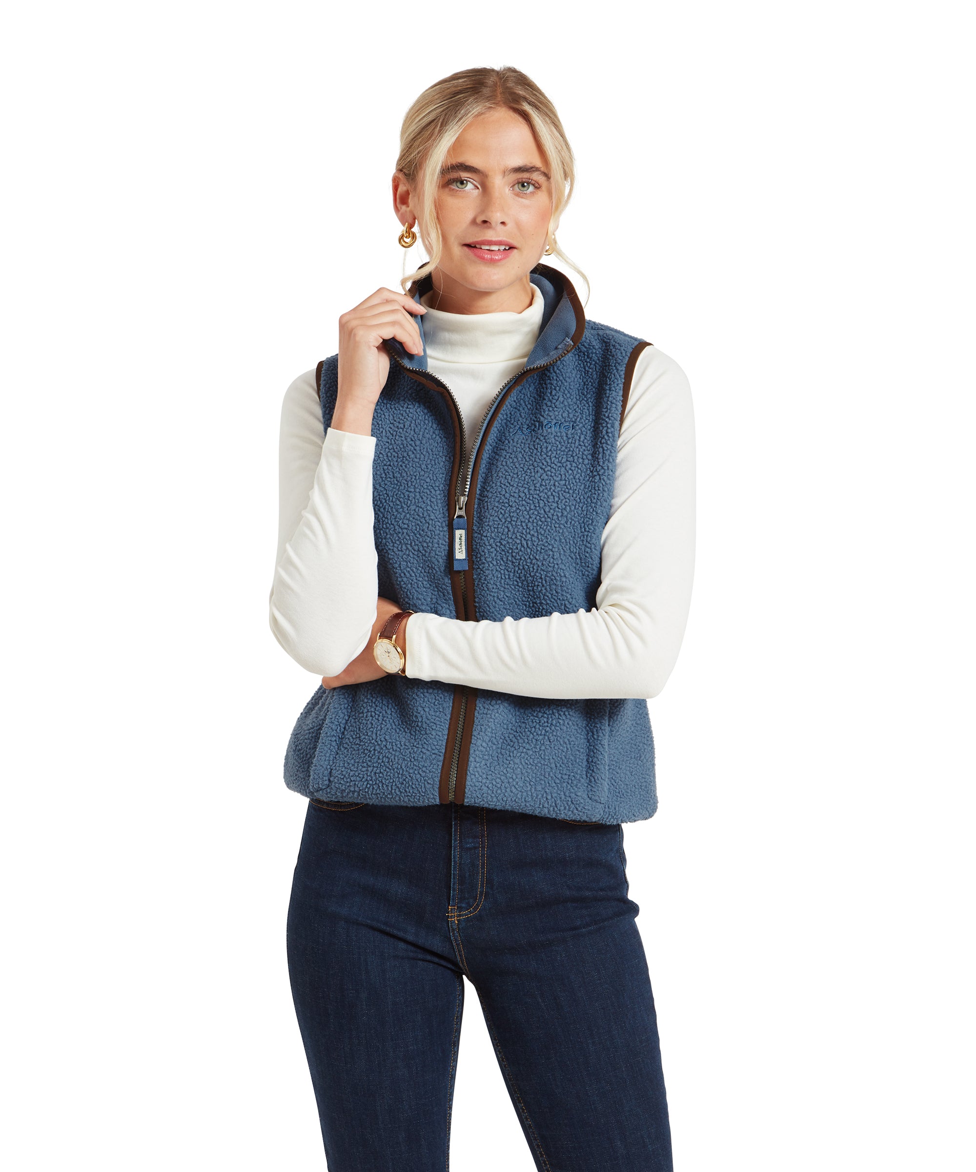 The woman standing with arms crossed, wearing the Schöffel Lyndon Retro Fleece Gilet for Women in Navy over a white turtleneck, looking confidently ahead.