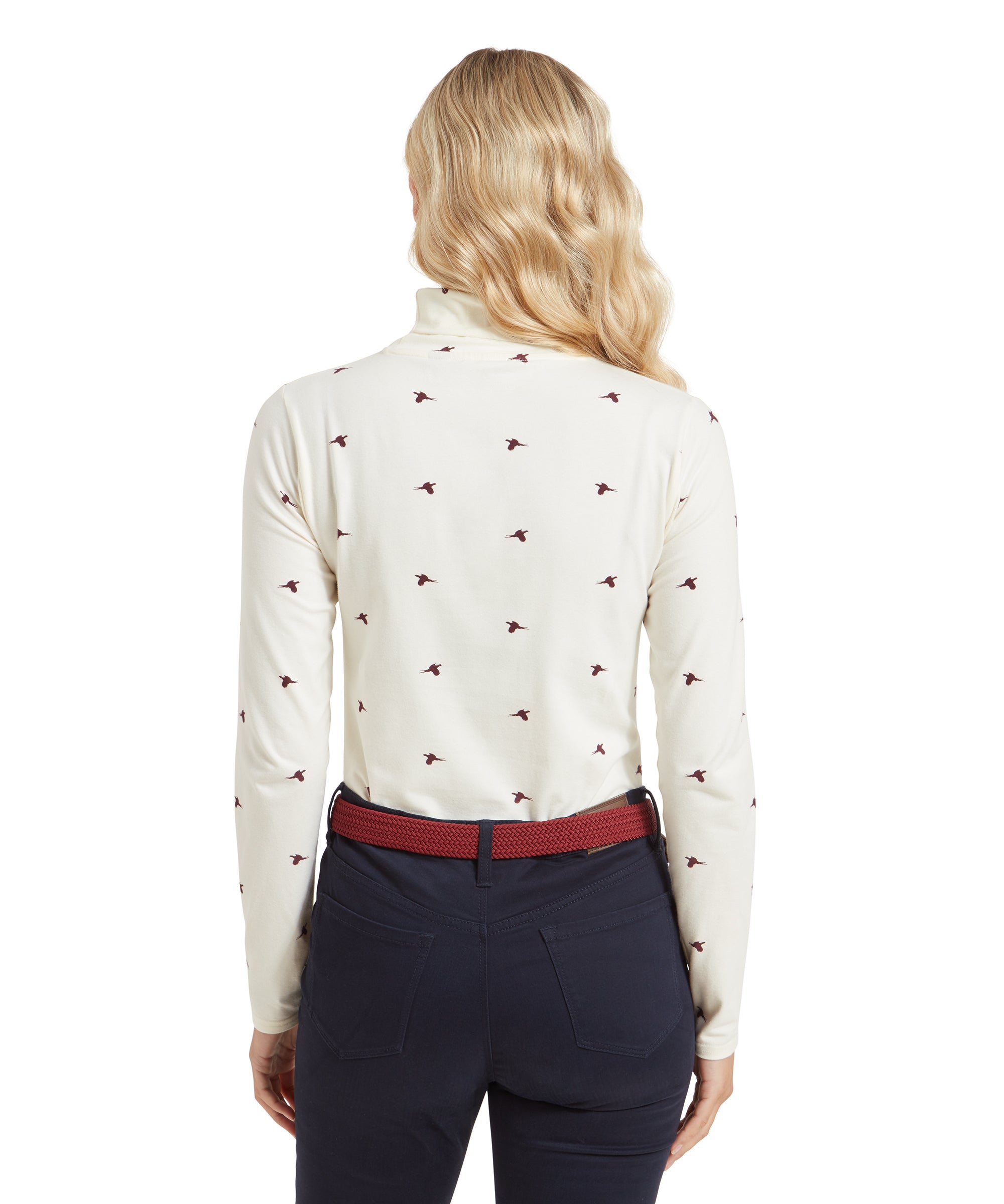 A rear view of a woman wearing a Schöffel Malham Top for Women in Red with maroon bird prints. She is also wearing dark navy pants with a red belt.