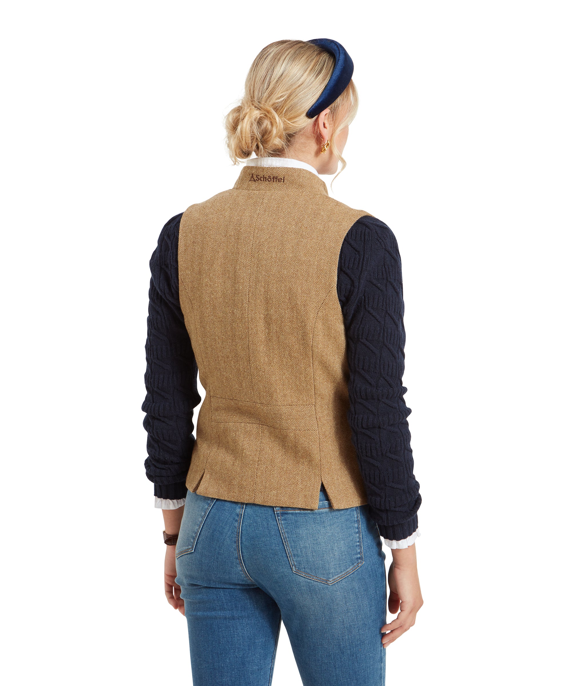 A back view of the woman wearing the Schöffel Millport Tweed Nehru Waistcoat for Womens in Light Brown, displaying the small logo at the back of the collar and the split hem detail.