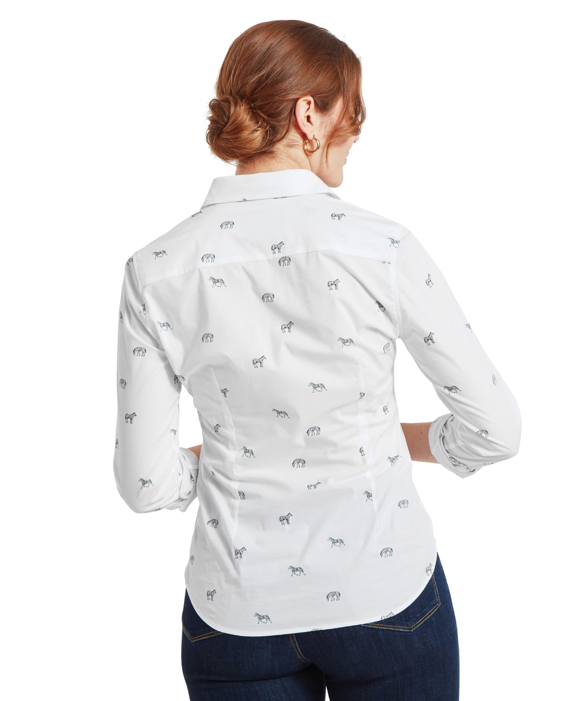 A rear view of the woman showcasing the back of the Schöffel Norfolk Shirt for Womens in White Black with small black zebra prints. The shirt is slightly fitted at the waist, and the woman’s hair is neatly styled in a low bun.