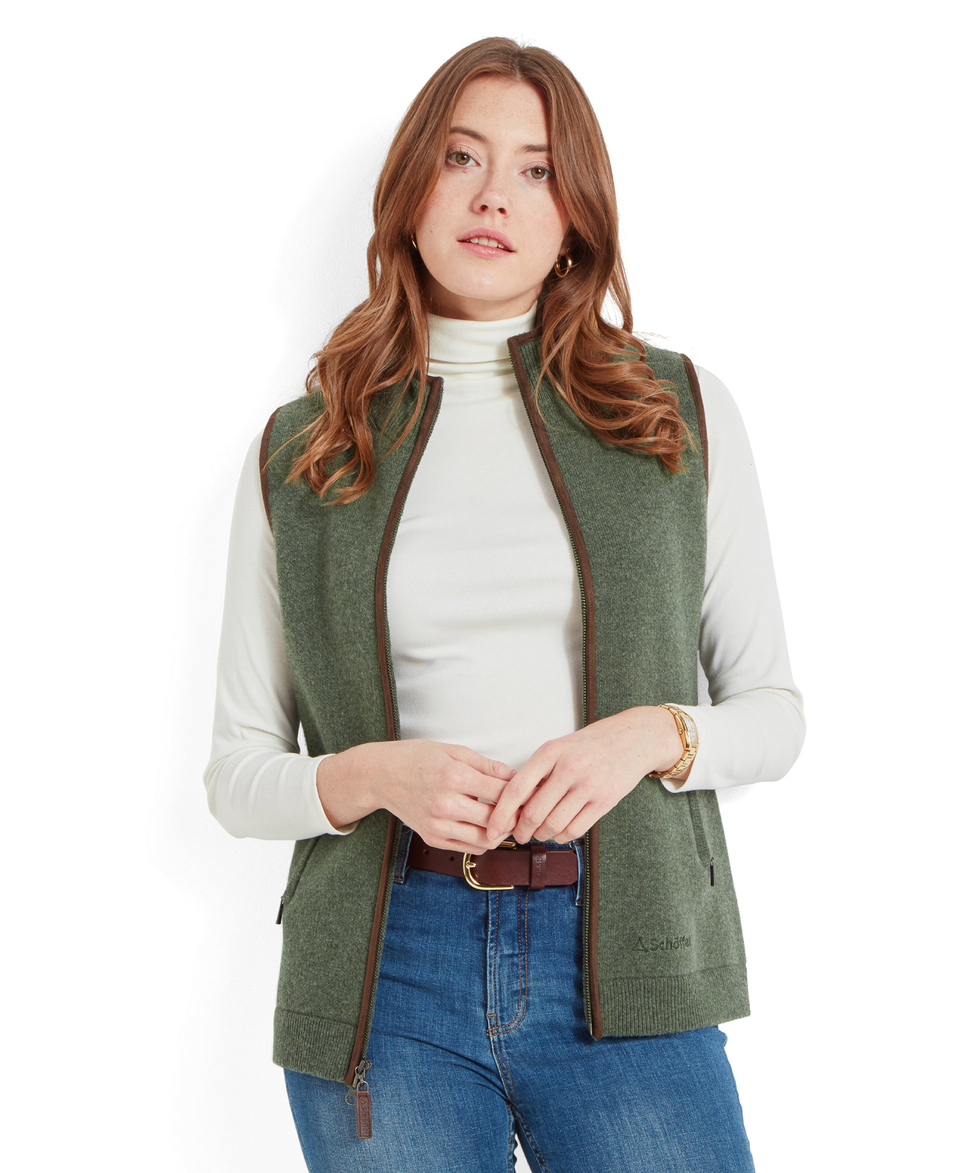 A woman wearing a Schöffel Women's Orkney Merino Gilet for Women in Green over a white turtleneck, looking at the camera with a neutral expression.