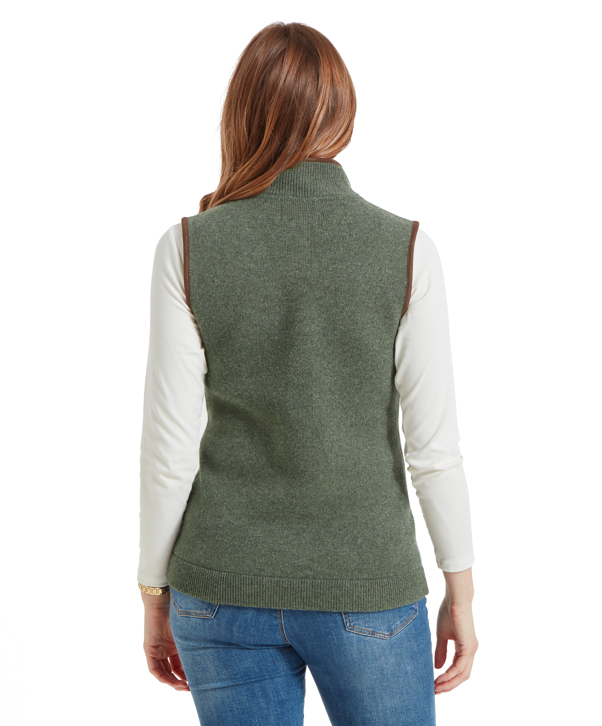 Rear view of a woman wearing a Schöffel Women's Orkney Merino Gilet for Women in Green and blue jeans, showing the back of the gilet.