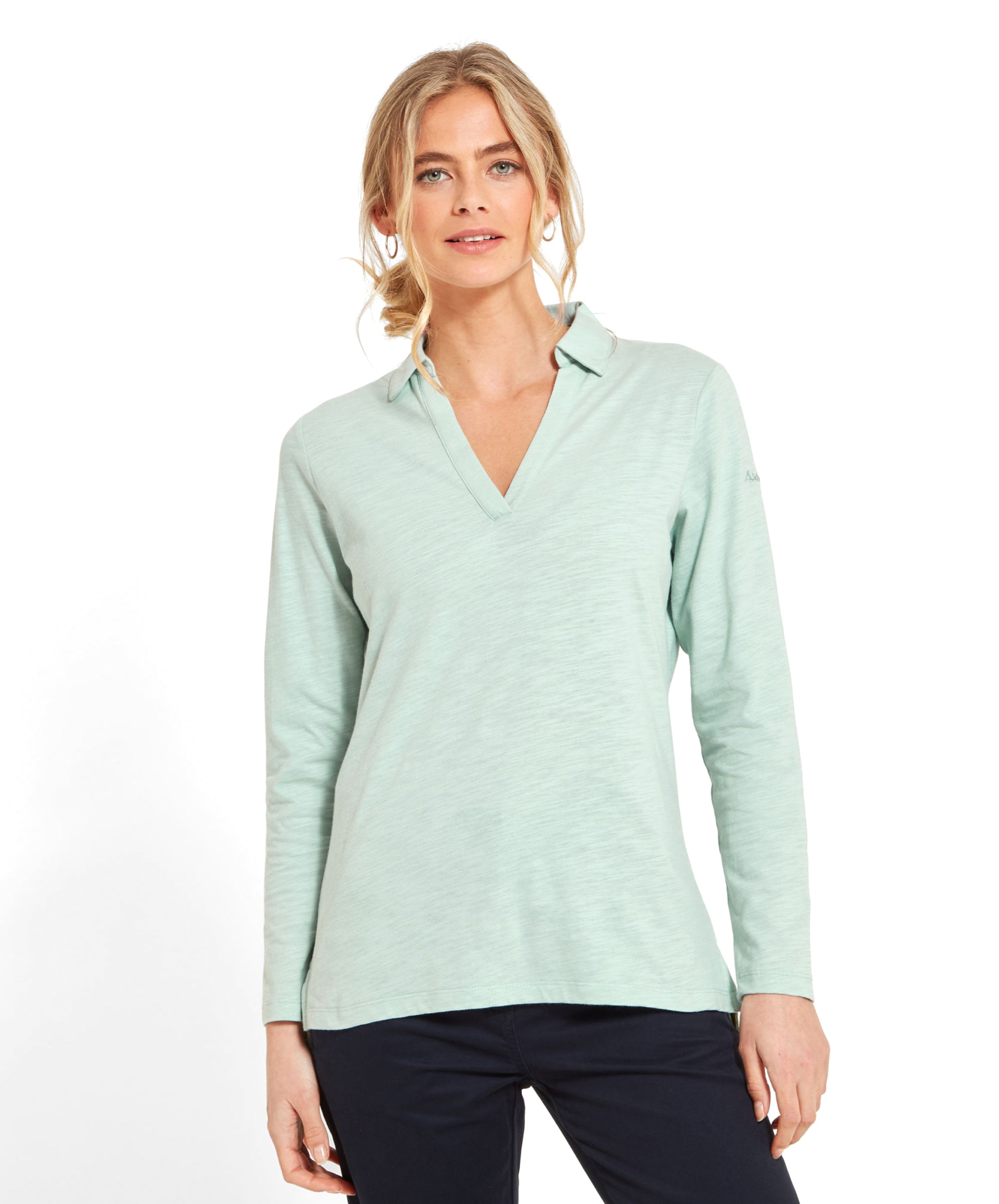 Woman wearing a Schöffel Pentle Bay Top for Women in Green with a V-neck collar, standing and smiling.