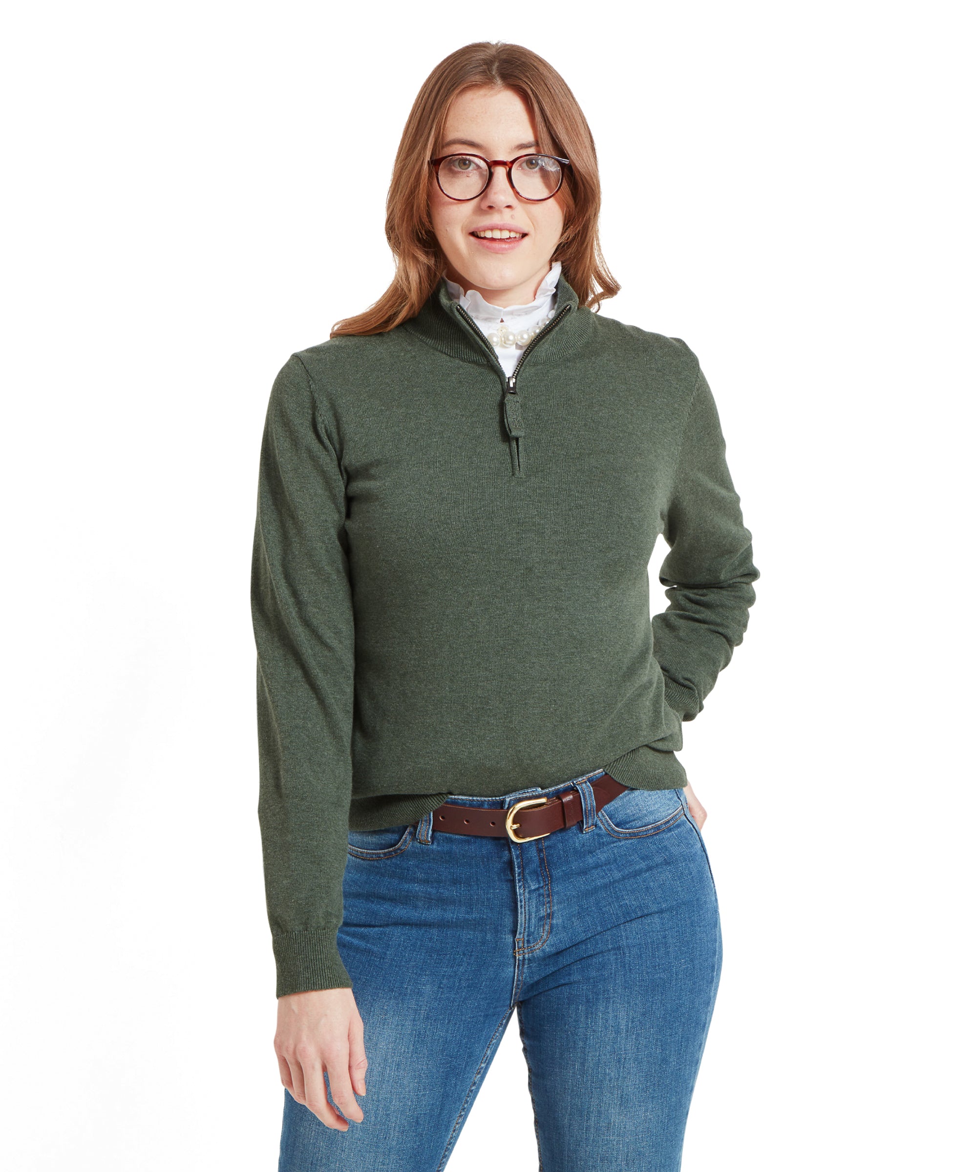 Woman wearing a Schöffel Polperro Pima Cotton 1/4 Zip for Women in Green with glasses, paired with blue jeans and a white shirt underneath, posing with her hands in her pockets.