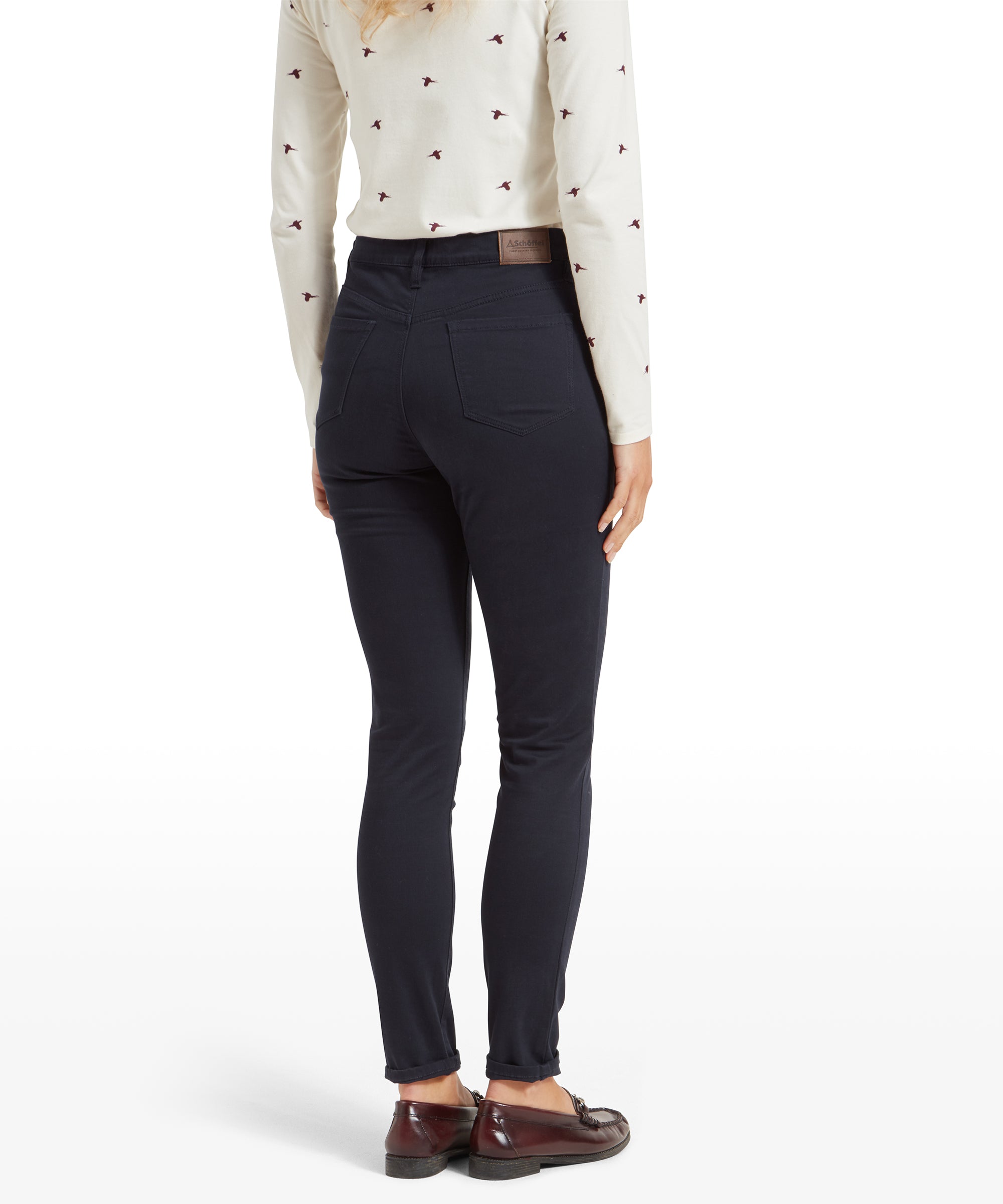 Rear view of a woman wearing Schöffel Poppy Jean for Womens in Navy with a high waist, showcasing the back pockets and brown leather brand patch above the right pocket.