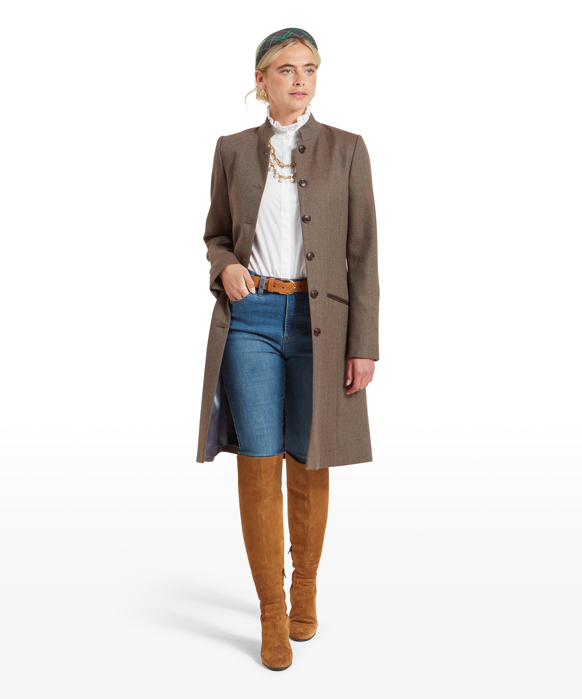 Woman wearing a Schöffel Portree Tweed Jacket for Women in Green with a high collar, standing confidently. The coat is buttoned up, and she is also wearing blue jeans and tan knee-high boots.