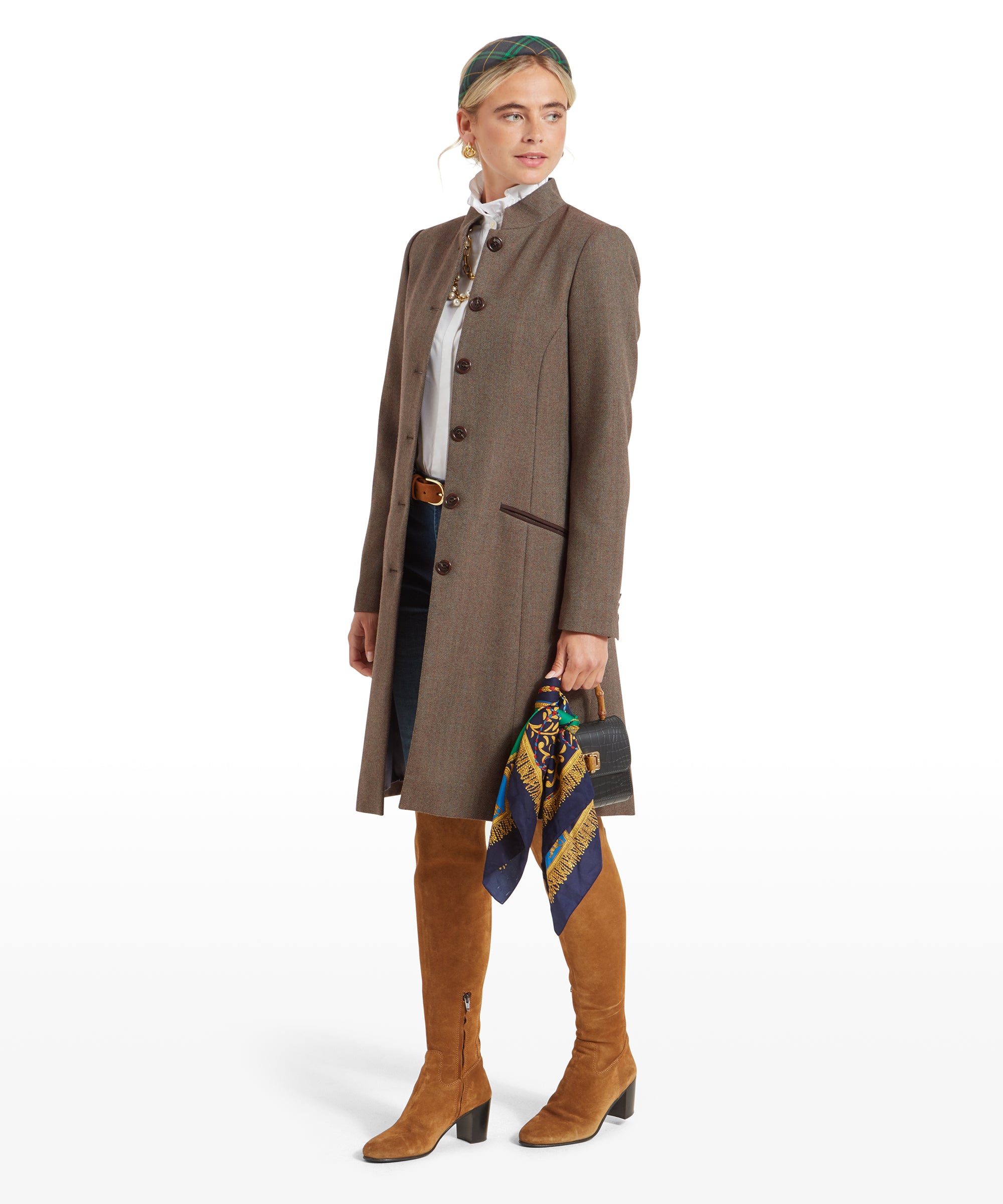 Woman in a Schöffel Portree Tweed Jacket for Women in Green holding a handbag and scarf, posing at an angle to show both the front and side of the coat.