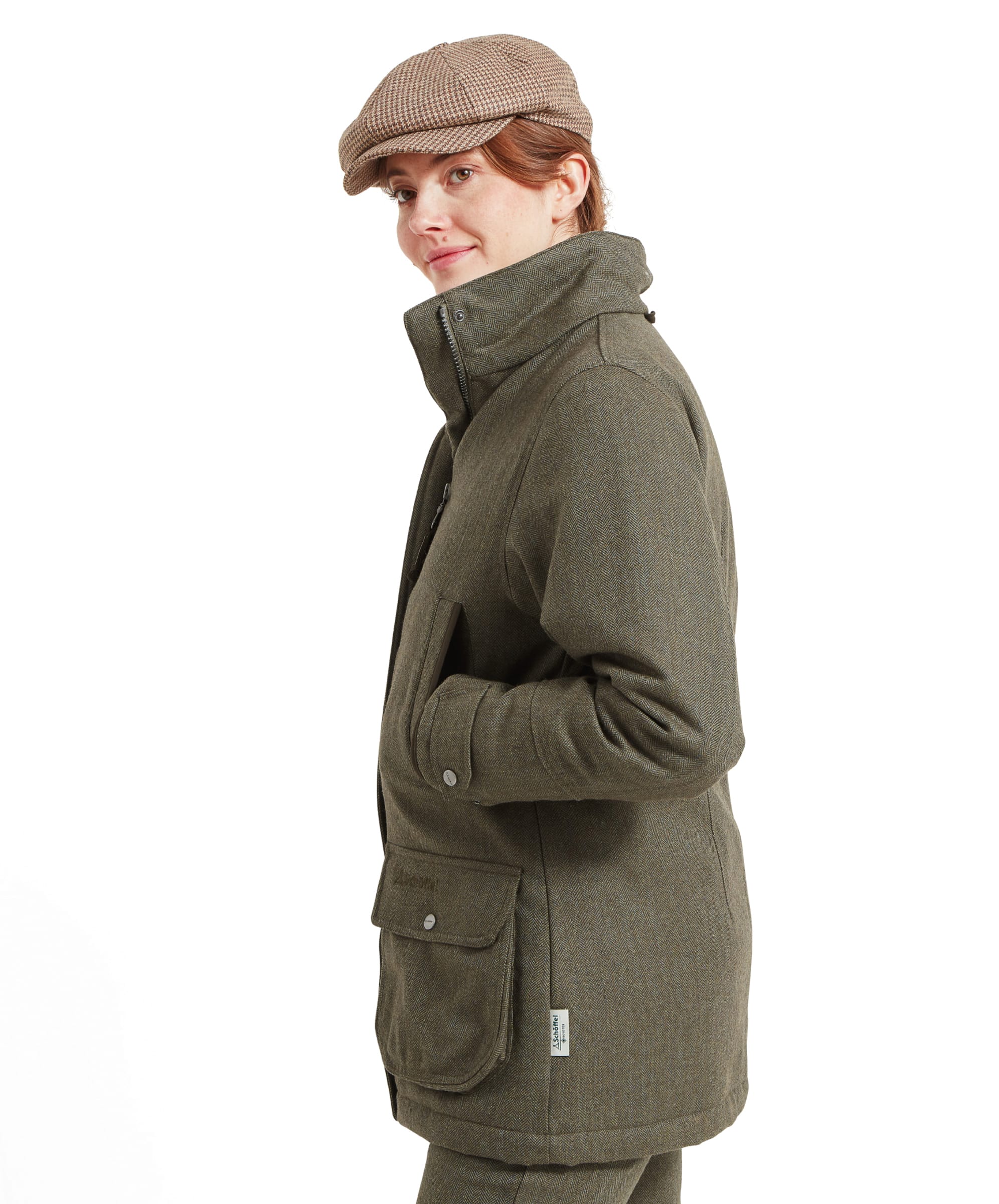 Side profile of the model wearing the Schöffel Ptarmigan Tweed Coat for Women in Green. The model’s hand is in her pocket, showing the coat's tailored fit and checker pattern.