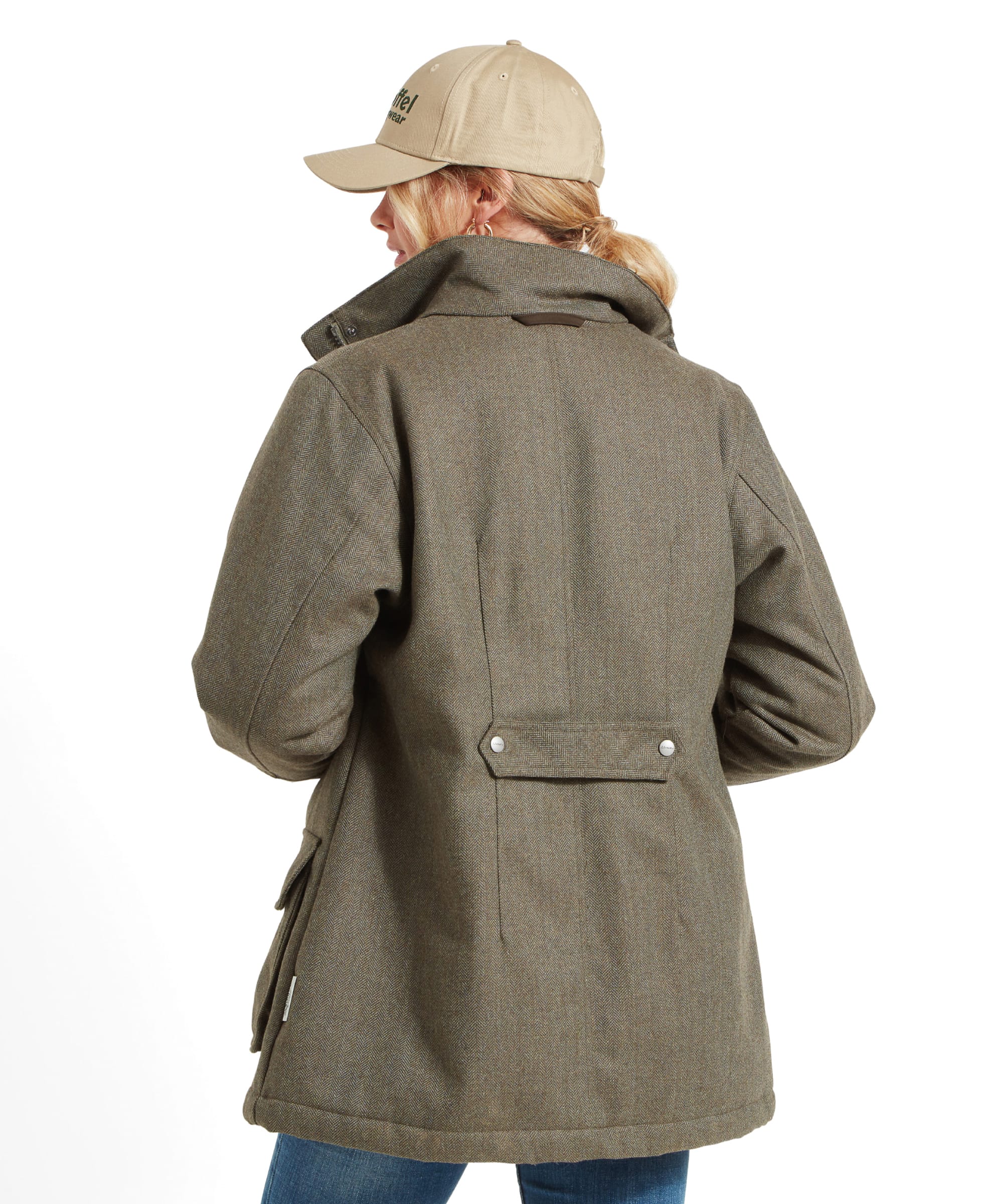 Rear view of a woman wearing a Schöffel Ptarmigan Tweed Coat for Women in Green and a beige flat cap, showing the back detail of the coat with a waist strap.