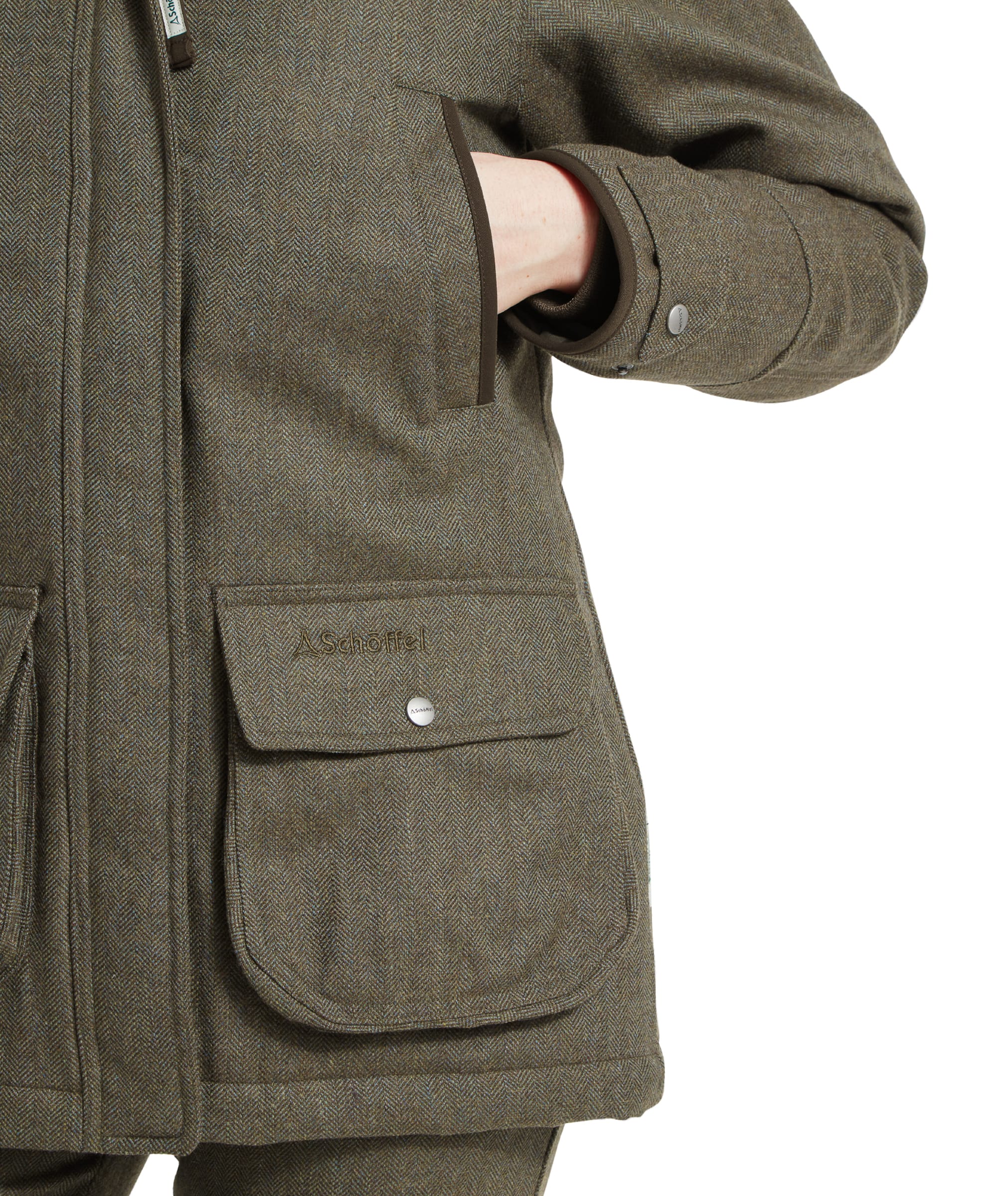 Close-up image of a Schöffel Ptarmigan Tweed Coat for Women in Green, showing the upper torso of a model. The model wears a scarf with a floral pattern inside the coat's collar, smiling slightly while looking down.