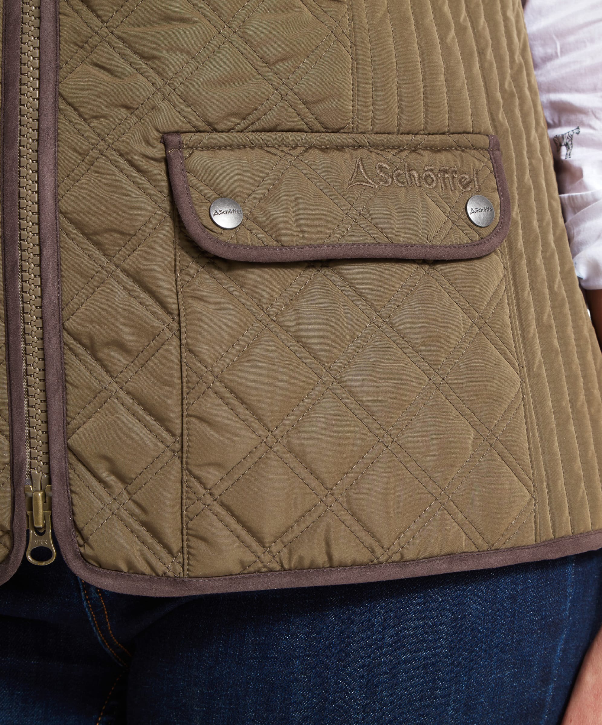 Close-up of the pocket detail on a Schöffel Quilt Gilet for Women in Green, showing the diamond quilt pattern, logo embroidery, and button flap pocket.