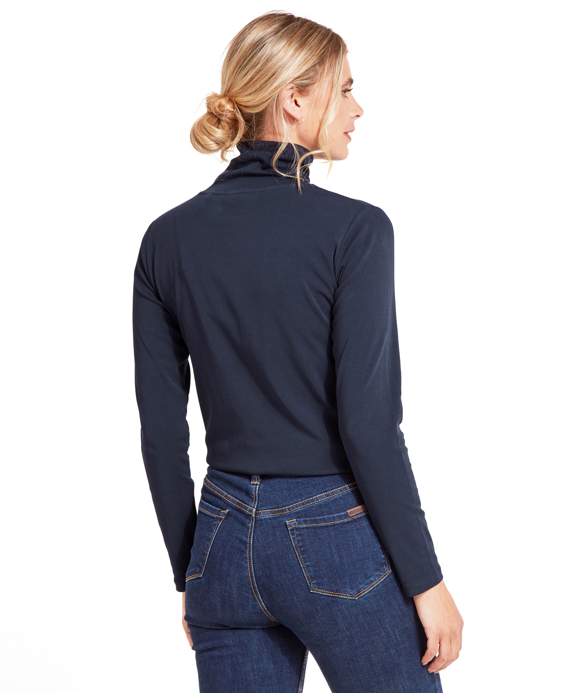 Rear view of the woman showcasing the back of the Schöffel Rosedale Roll Neck for Women in Navy and jeans.